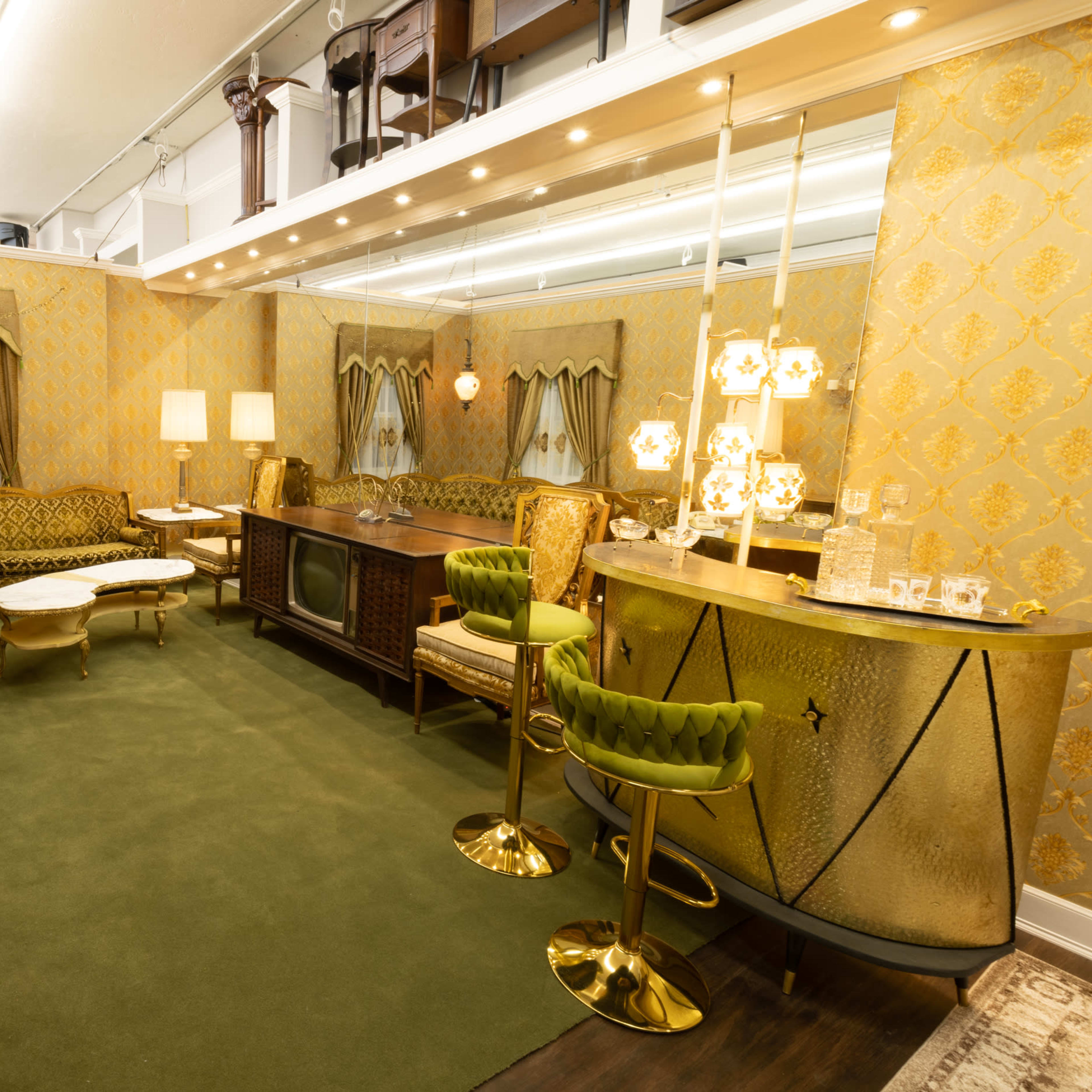 A vintage living room with yellow patterned wallpaper, a green carpet, a sofa, a coffee table, and a bar cart.