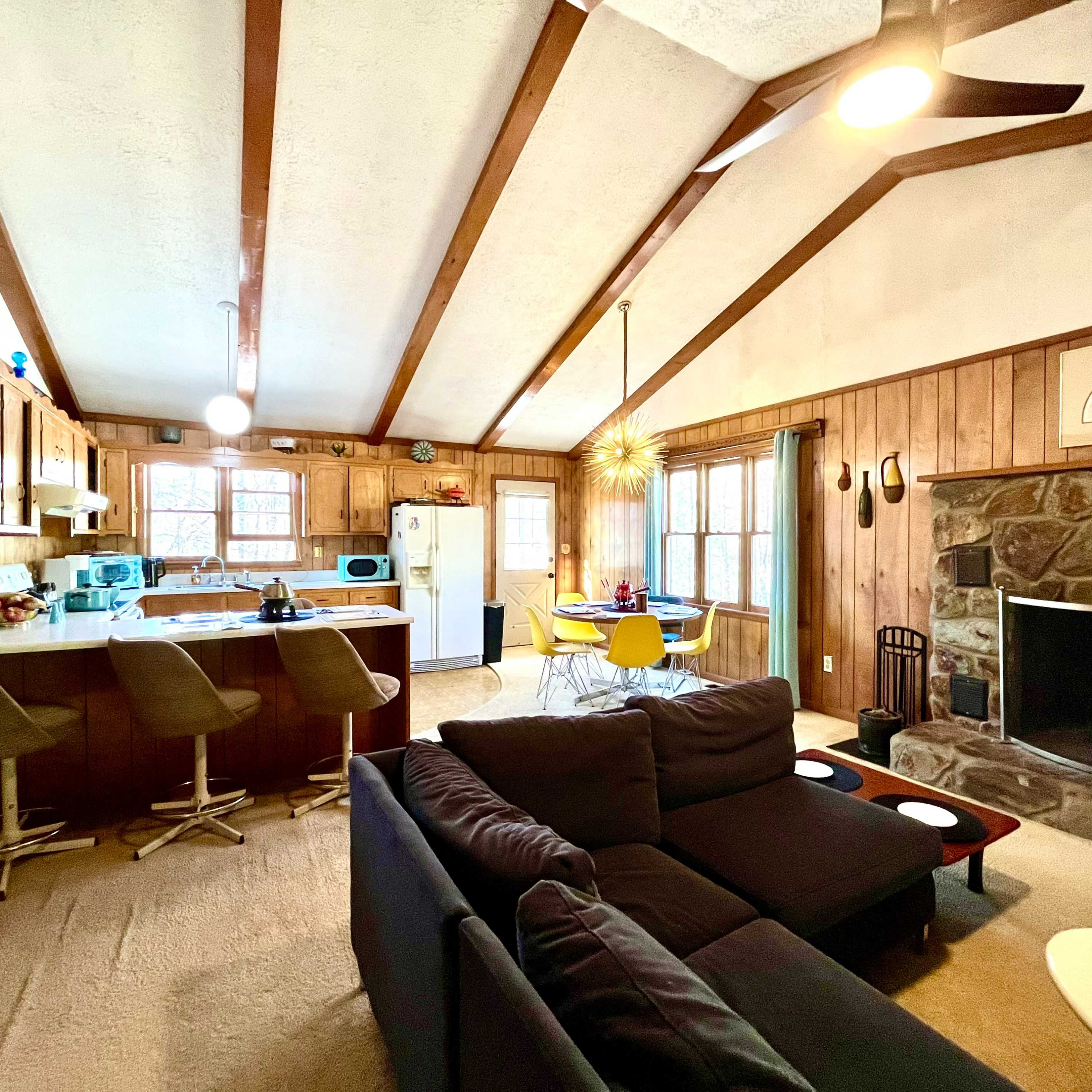 A spacious living area with a kitchen counter, a stone fireplace, and a cozy seating arrangement.