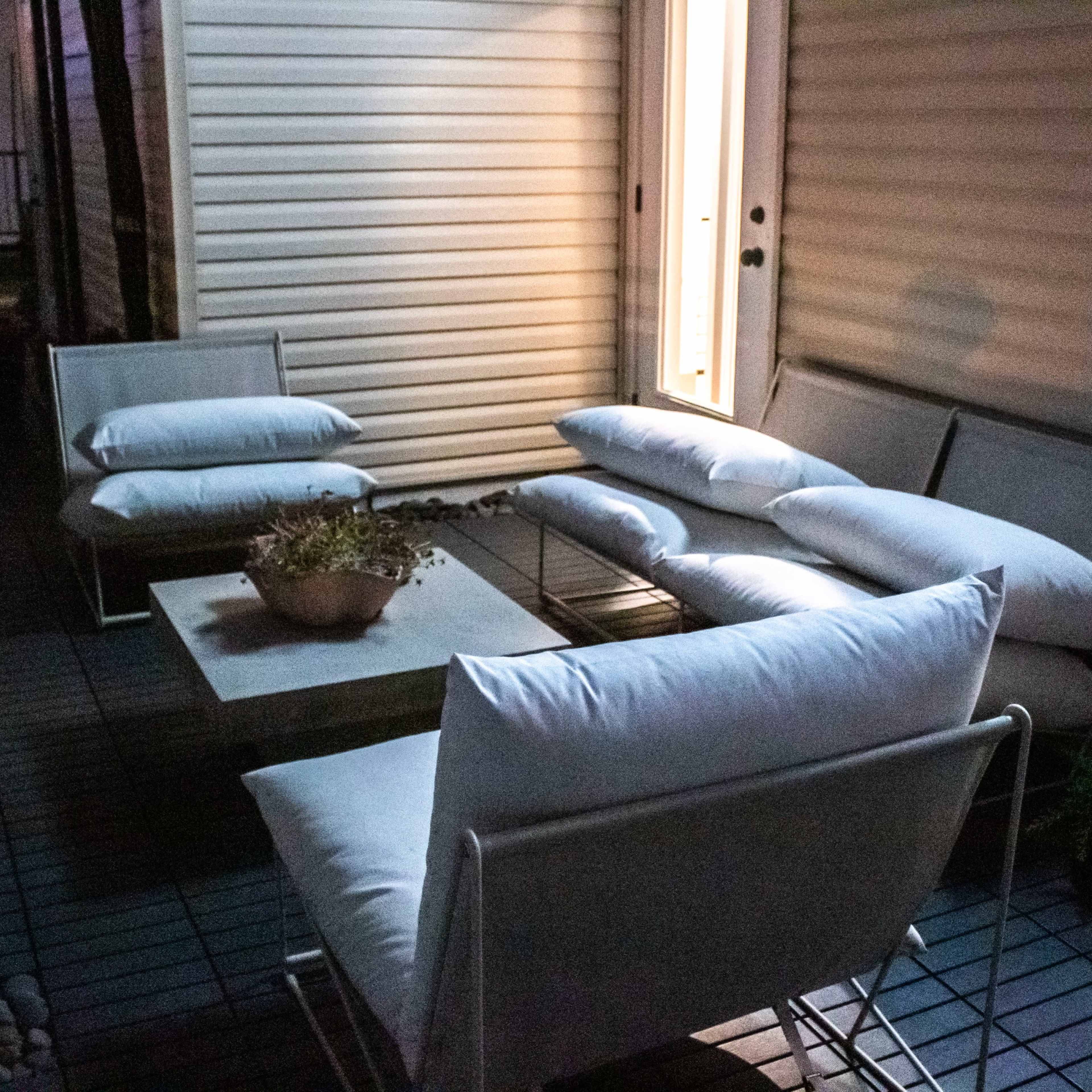 A small outdoor seating area features white sofas and a low table, illuminated by soft light from a nearby door.