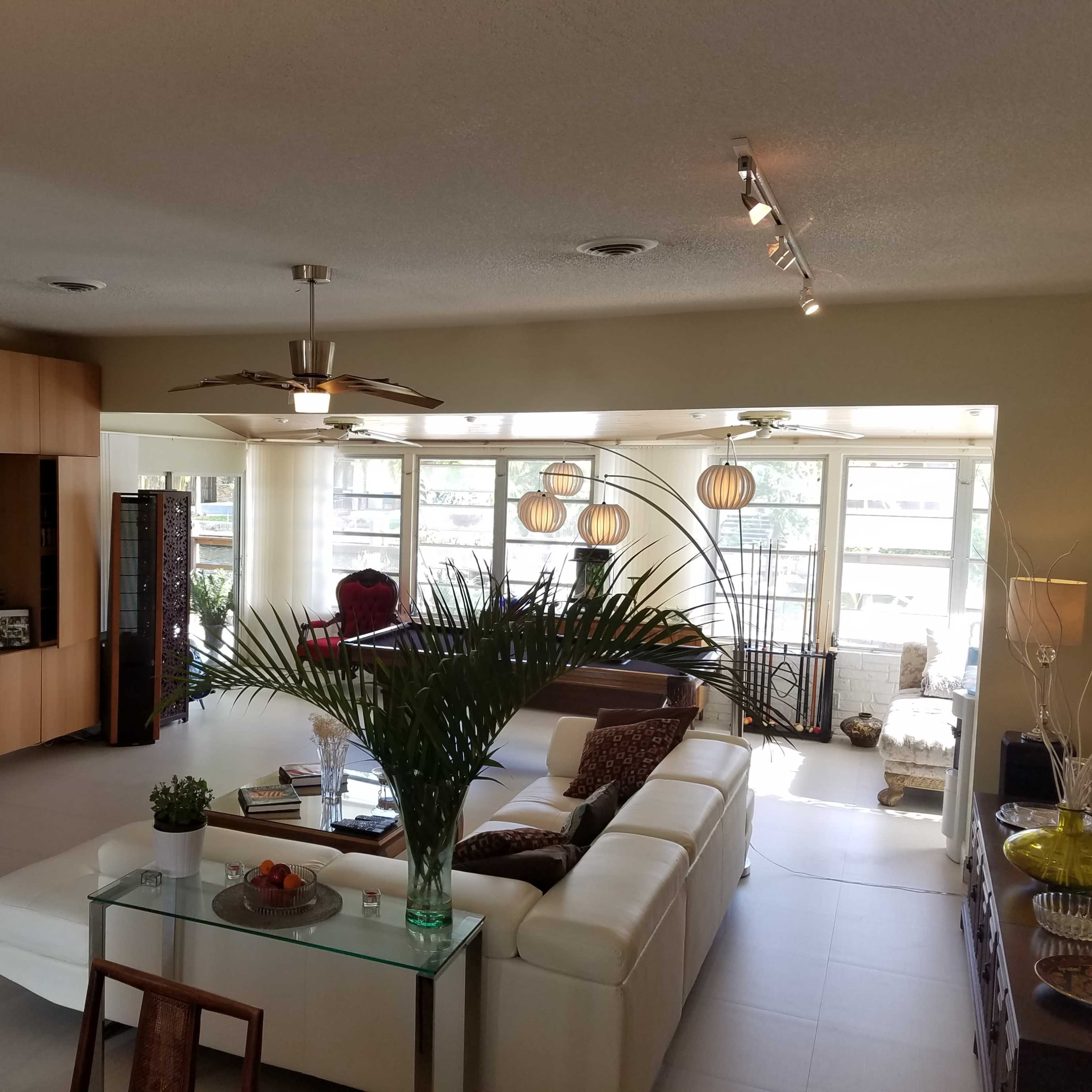 A spacious living room features modern furniture, a flat-screen TV, and large windows allowing natural light to fill the space.