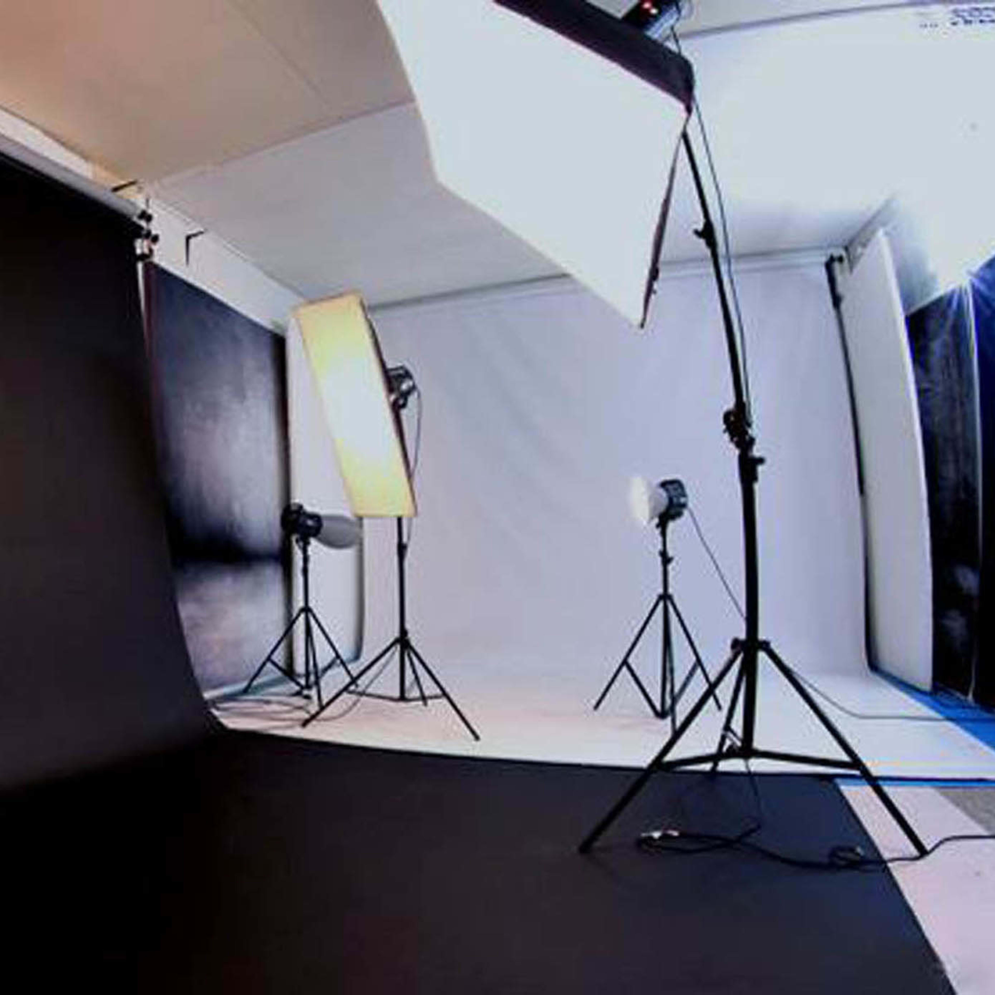 A photography studio setup with multiple lighting equipment and a dark backdrop.