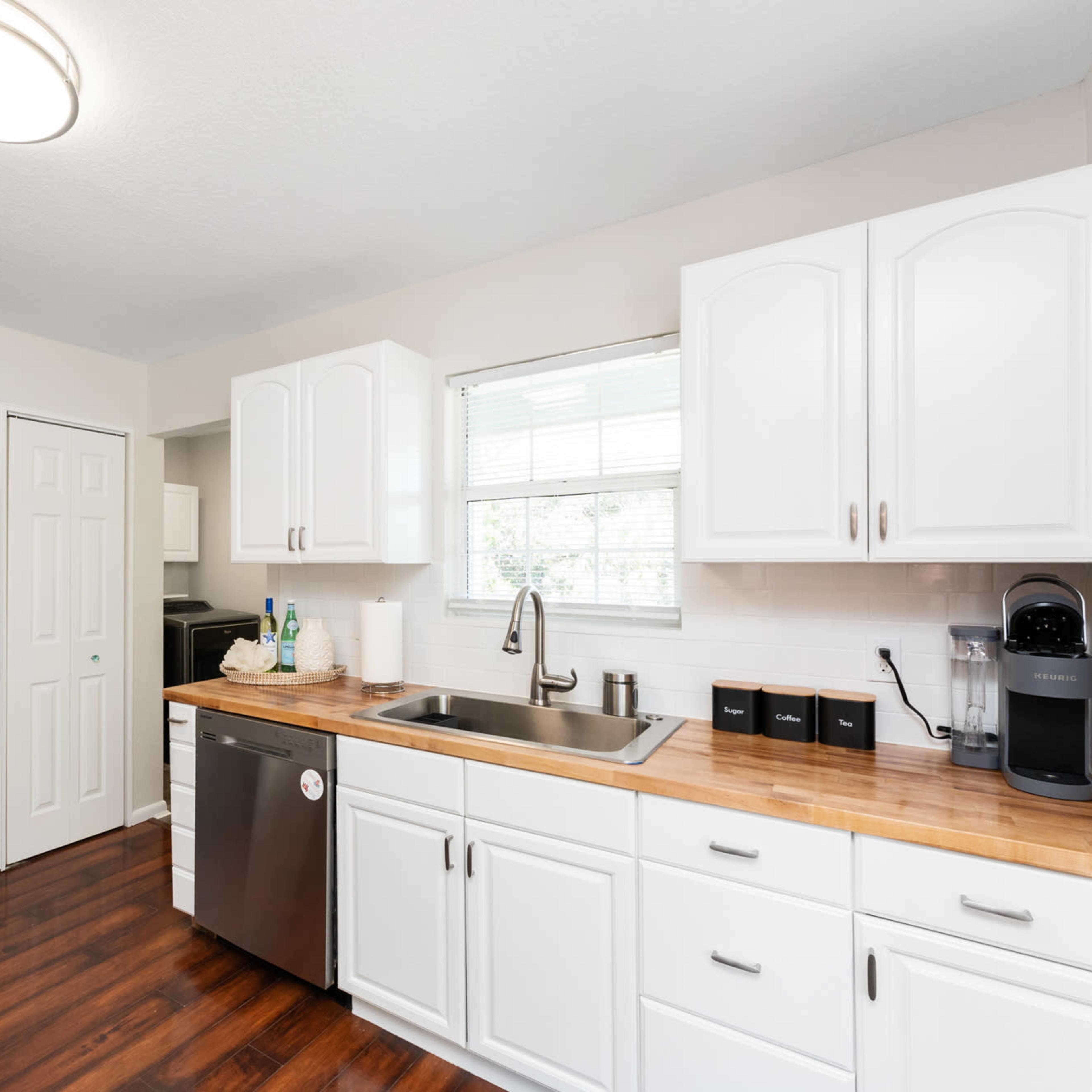 A modern kitchen featuring stainless steel appliances, white cabinetry, and a wooden countertop.