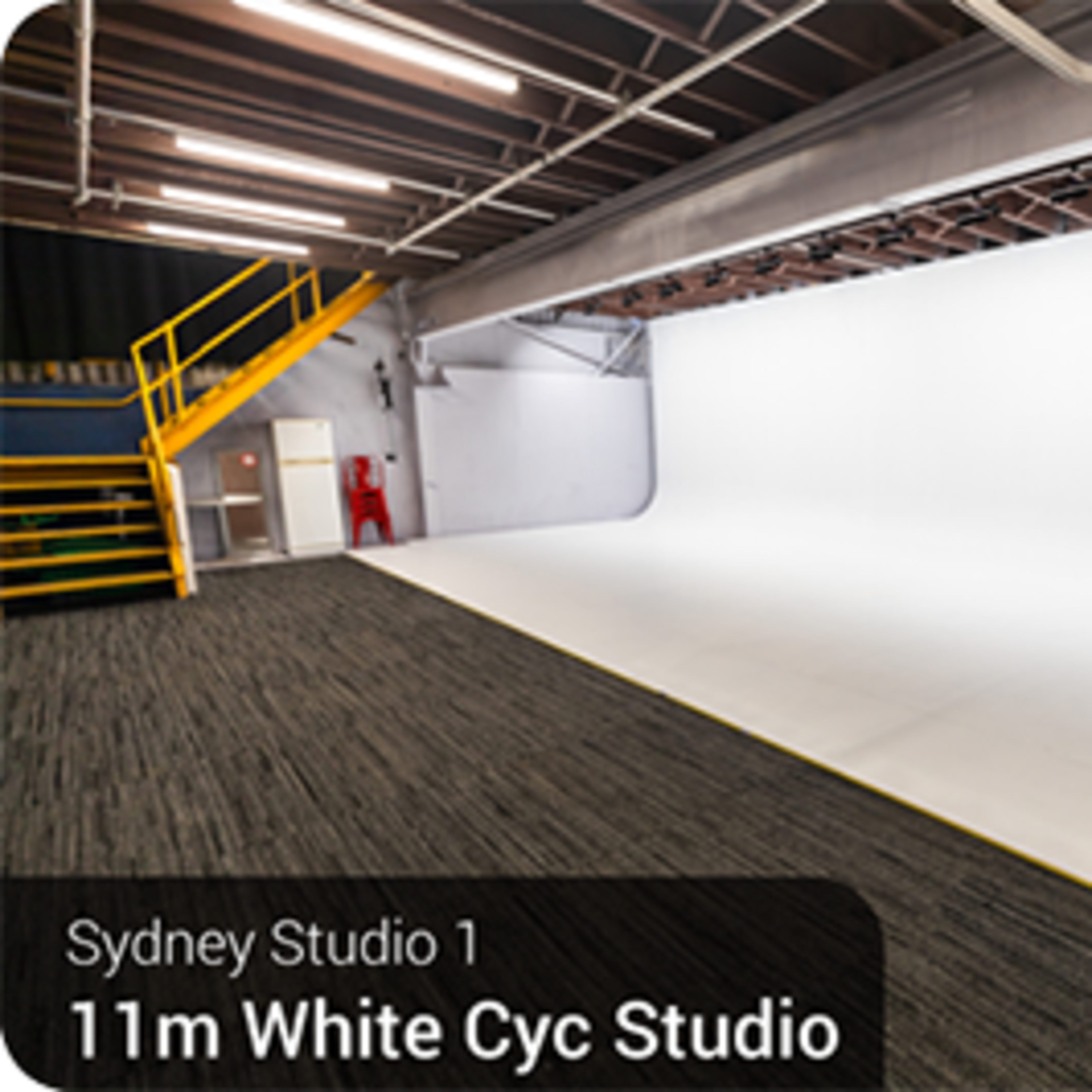 A large white cyc studio with a seamless backdrop and a staircase leading to an upper level.