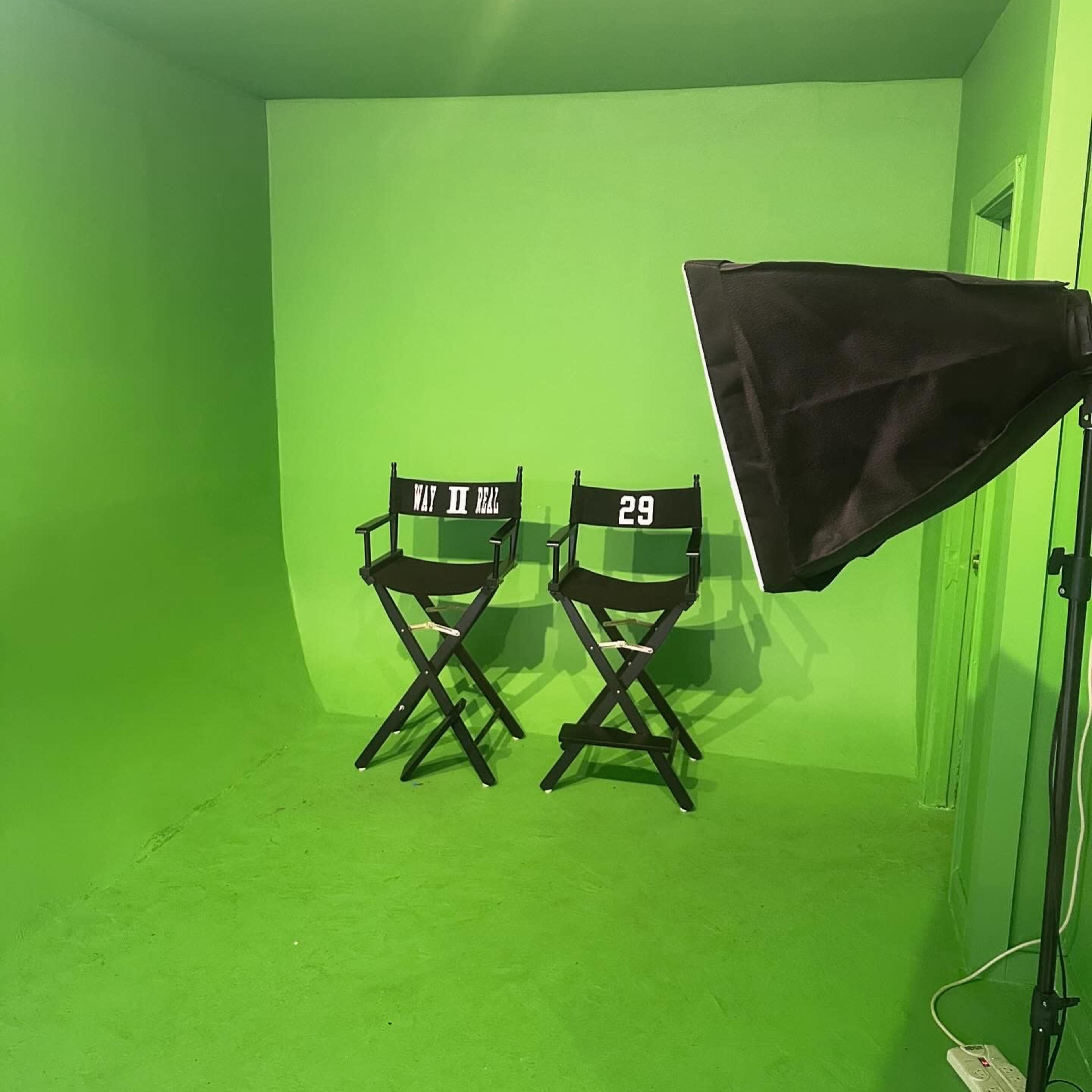 A green screen room with two director's chairs and a light source in the corner.
