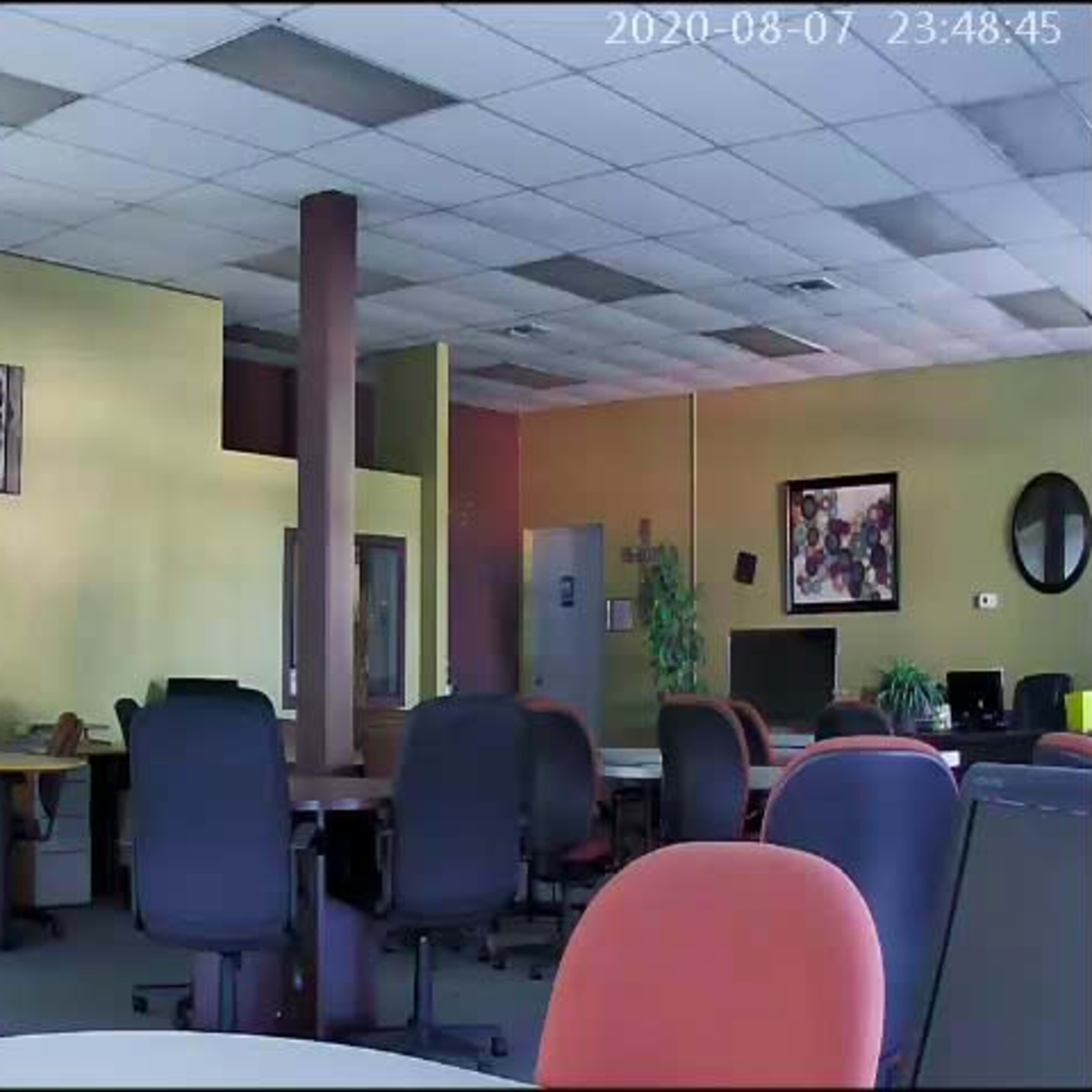 A spacious office interior with several desks and computer stations, along with a few chairs and decorations on the walls.