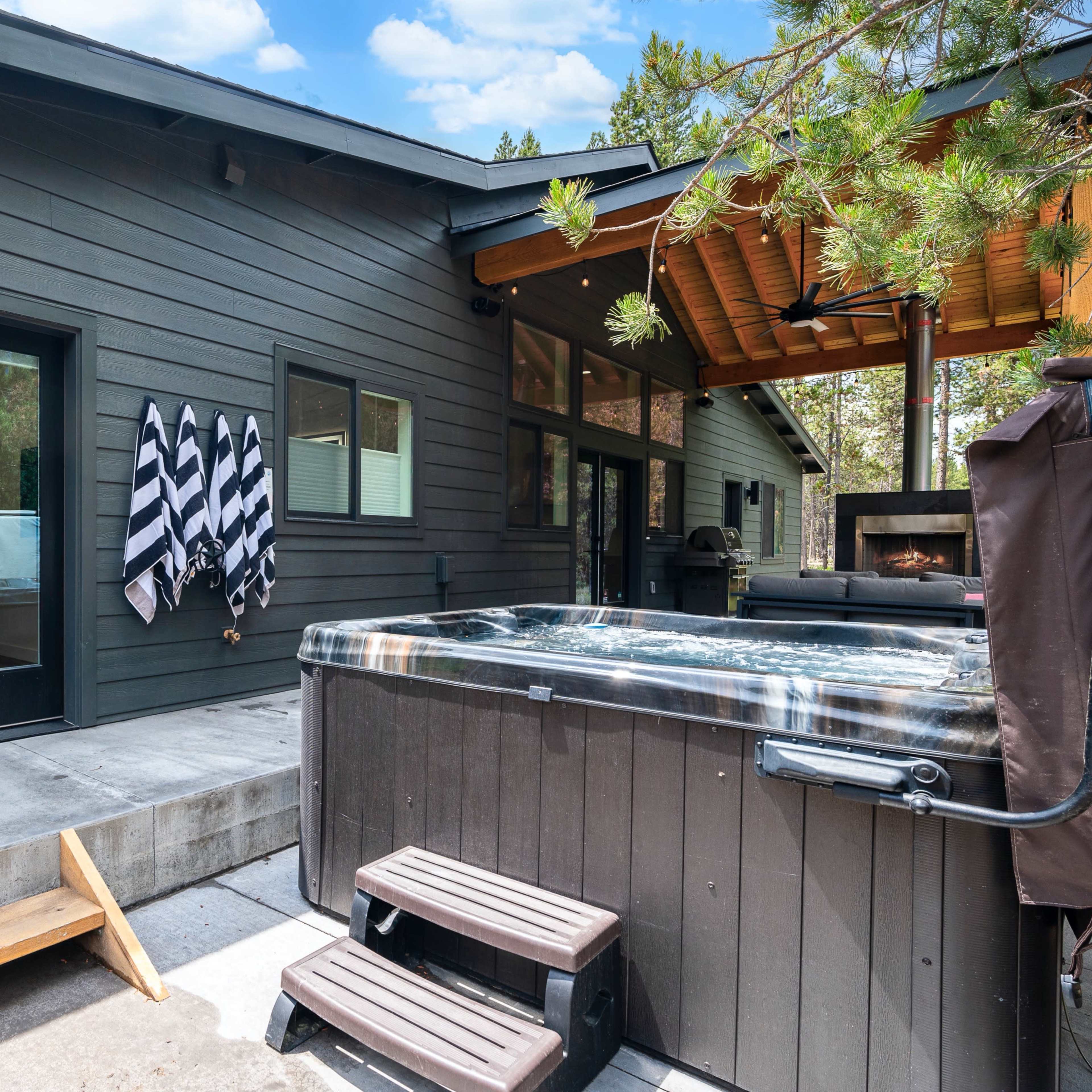 A modern house with a hot tub on a patio, featuring black and white striped towels hanging on a wall nearby.