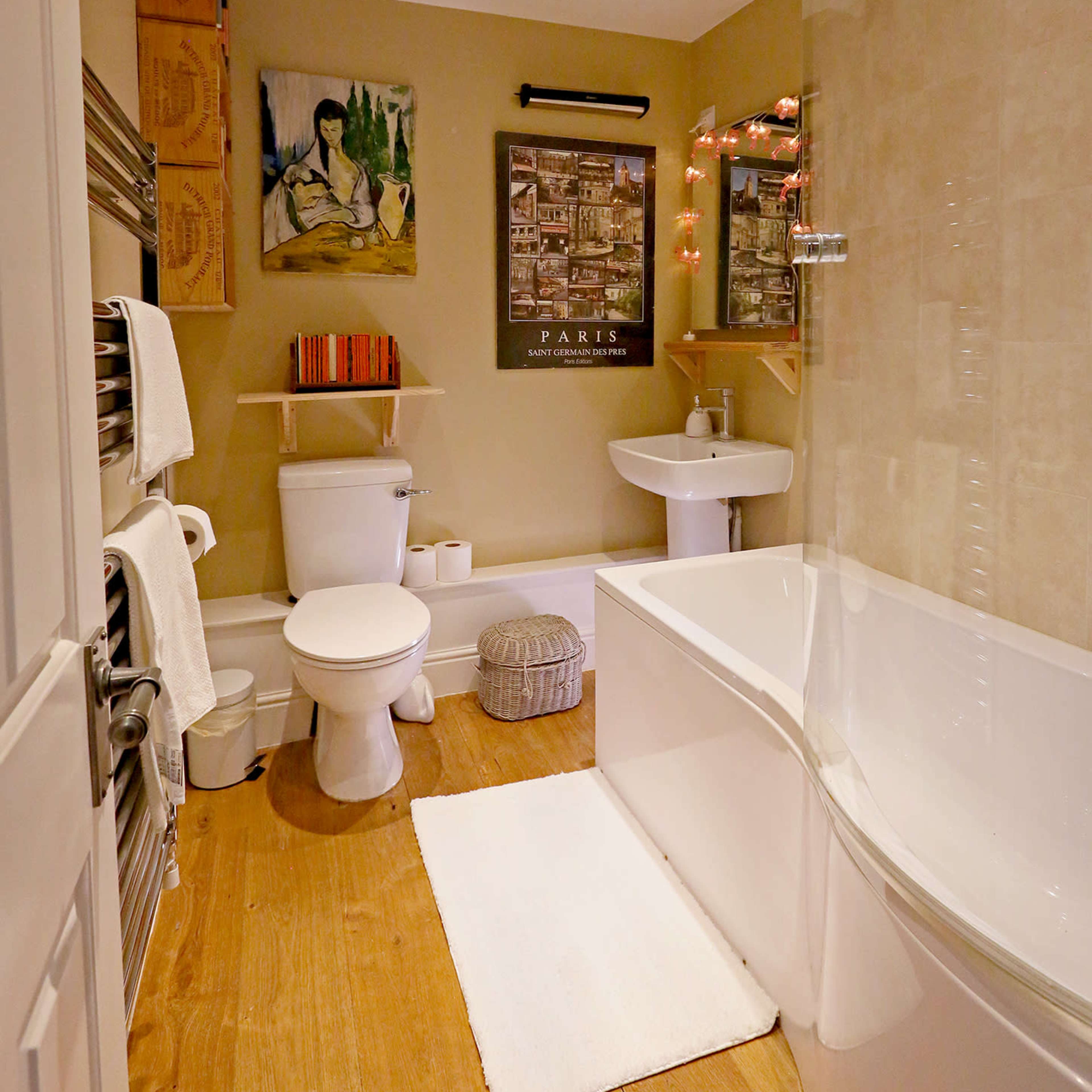 A modern bathroom with a bathtub, toilet, sink, and decorative wall art.
