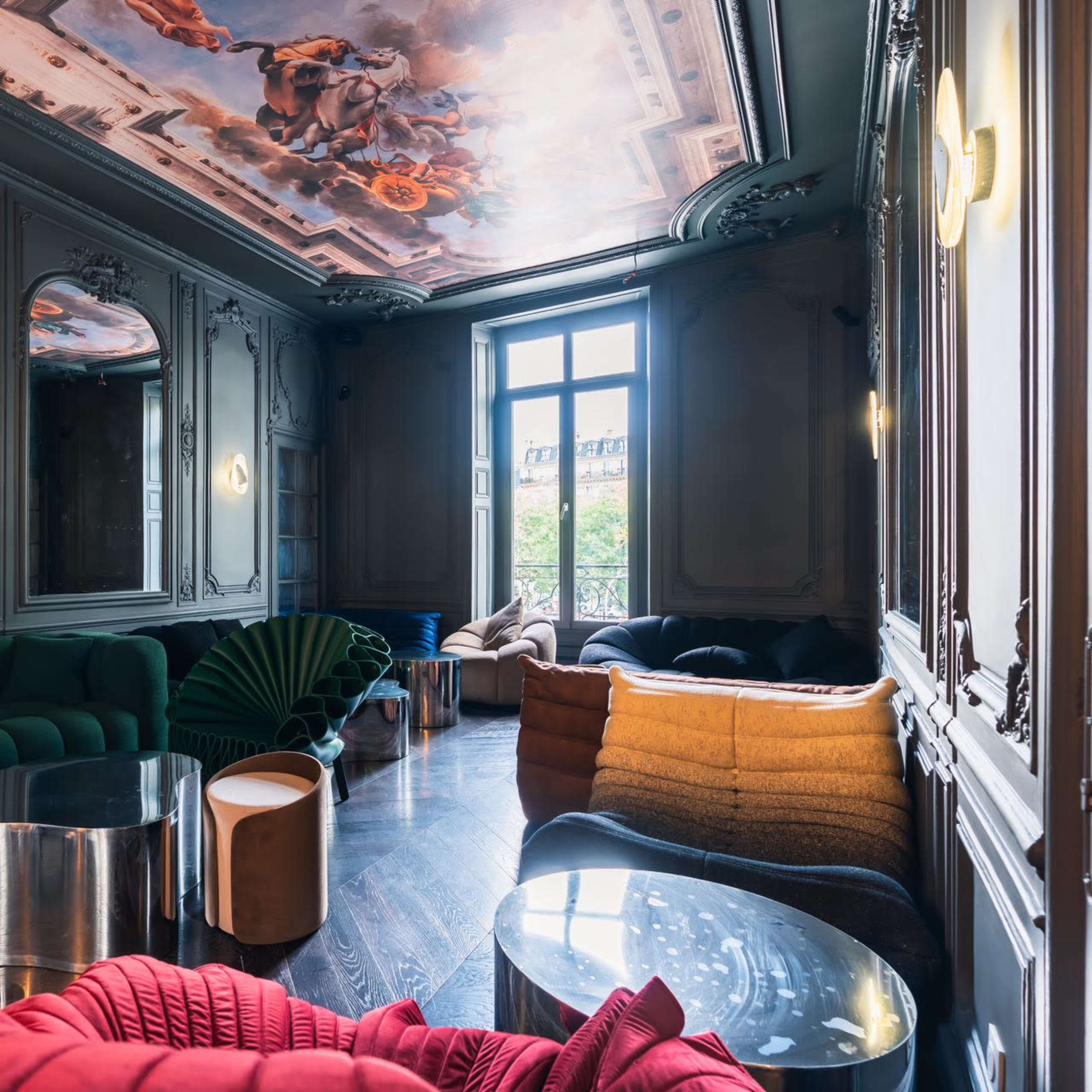 An elegant interior with decorative walls and a painted ceiling, featuring various modern furniture pieces in different colors and textures.