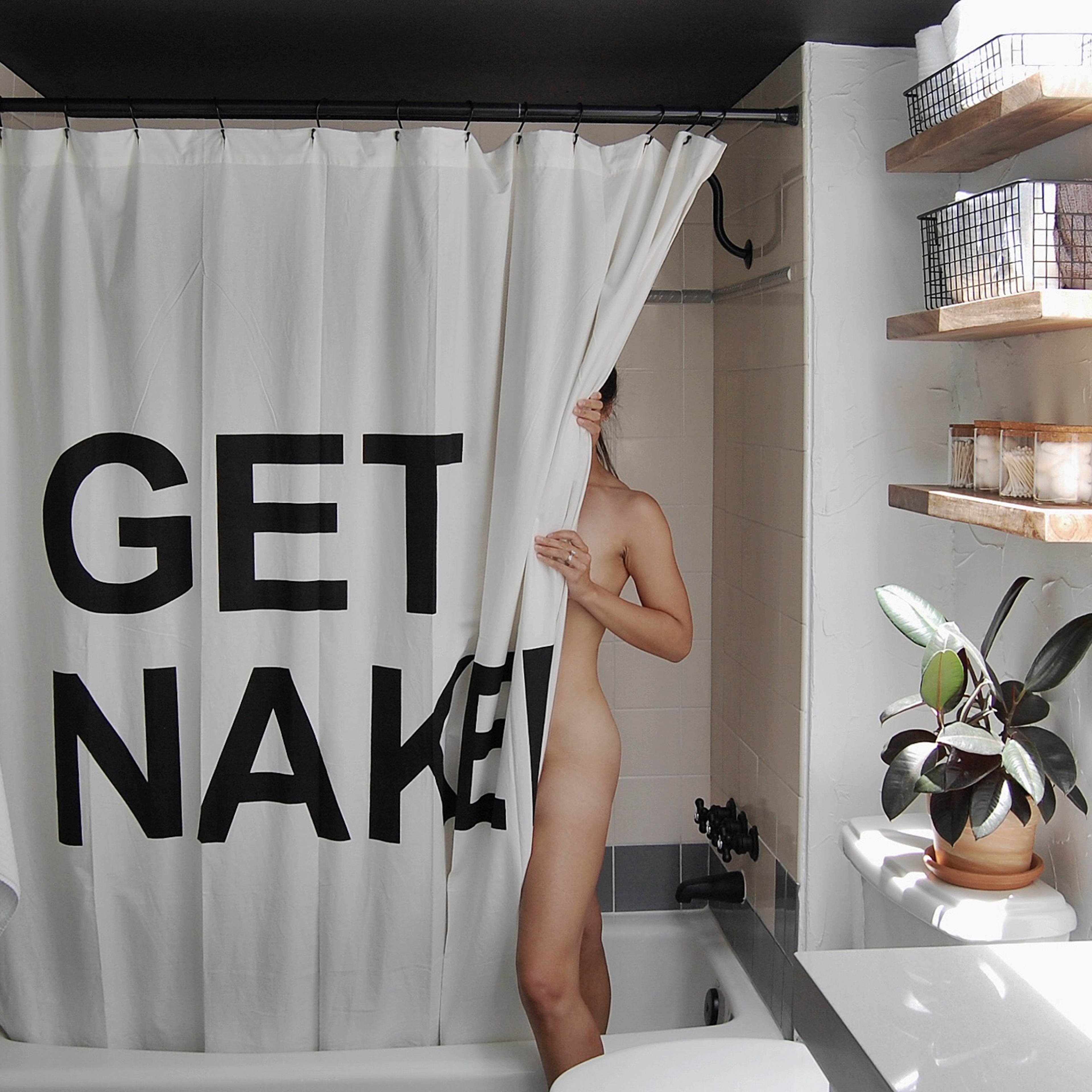 A person partially steps out from behind a shower curtain with large text that reads "GET NAKED" in a bathroom setting.