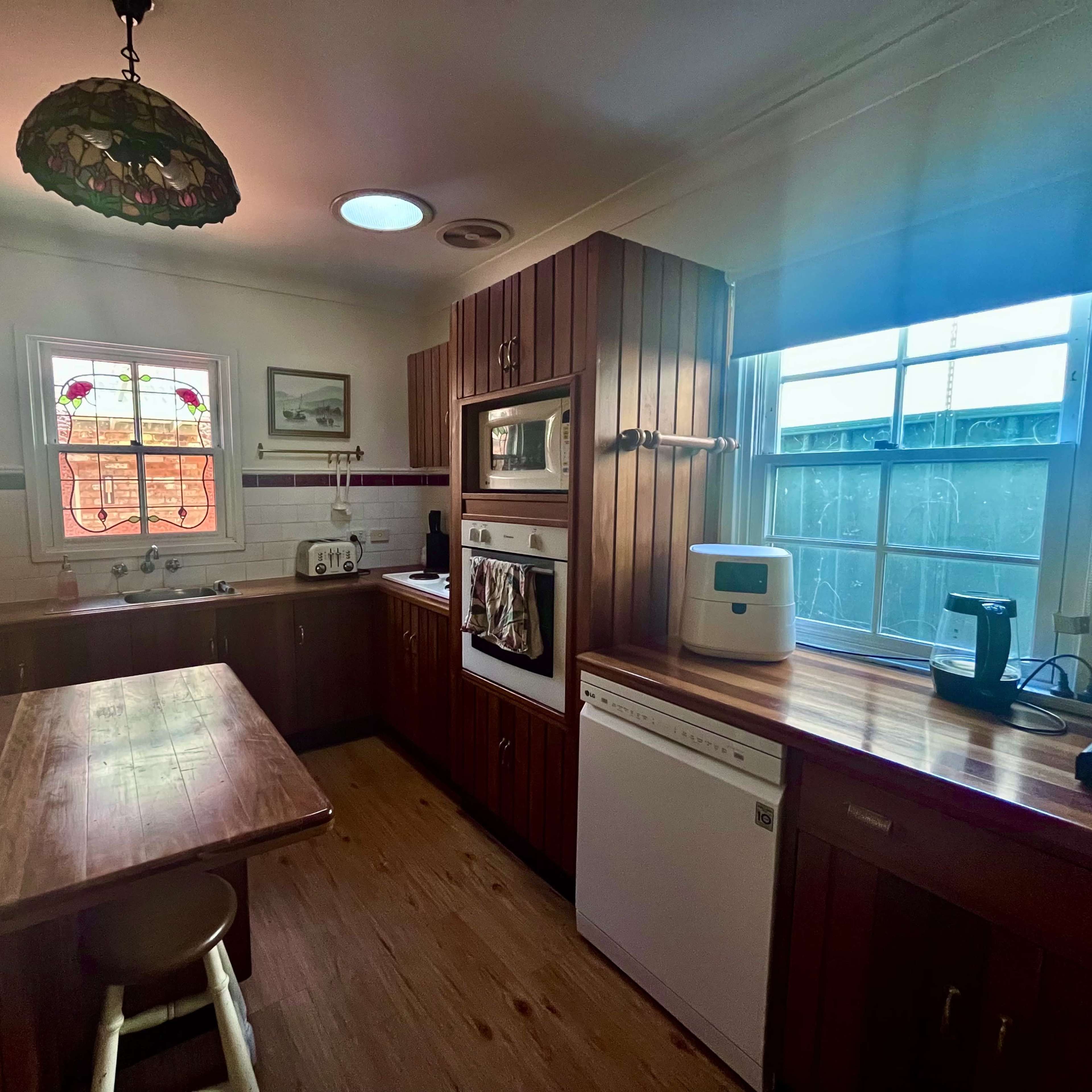A kitchen with wooden cabinetry, a central wooden table, and modern appliances including an oven and a refrigerator.