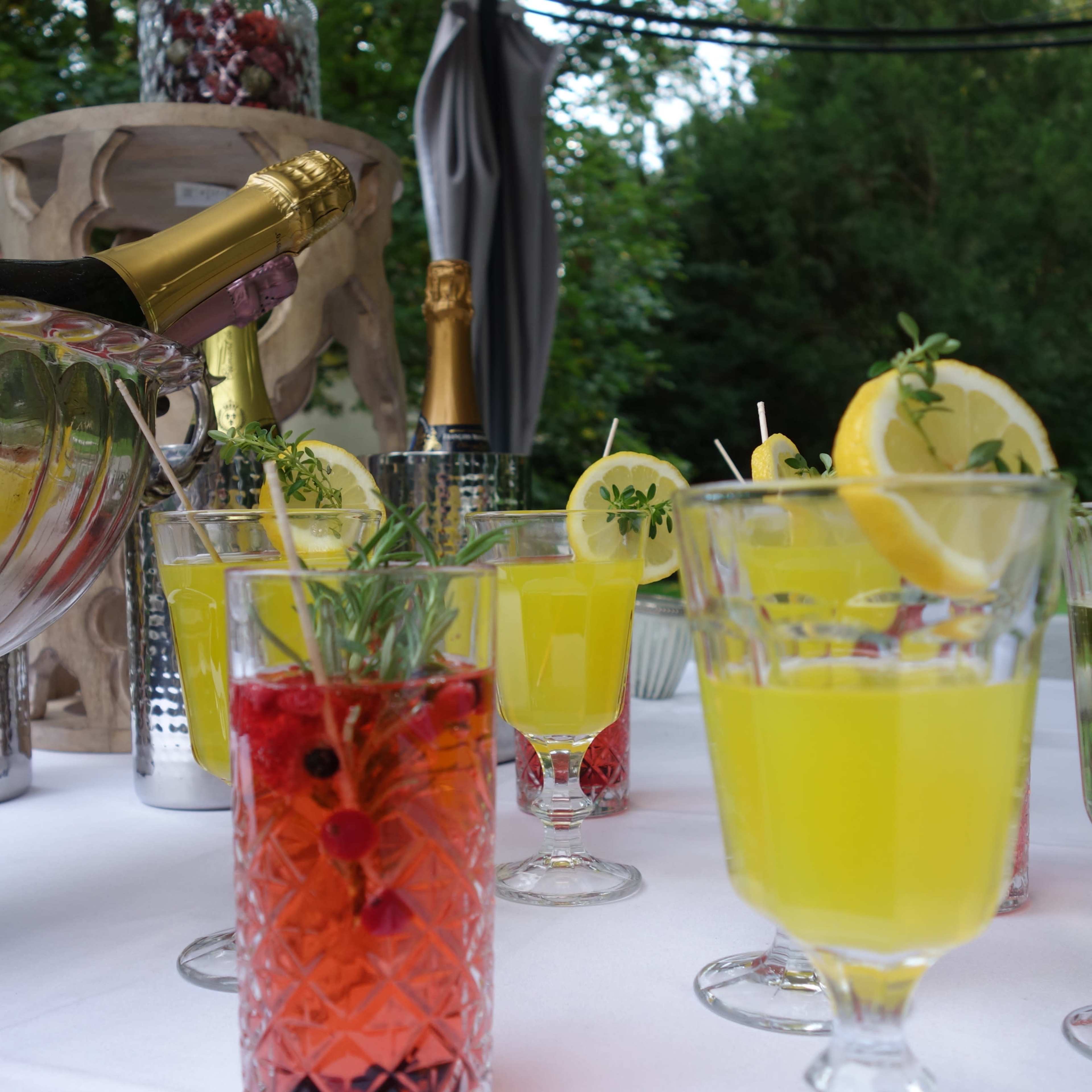 A selection of colorful drinks is arranged on a table next to a champagne bottle in a silver ice bucket.