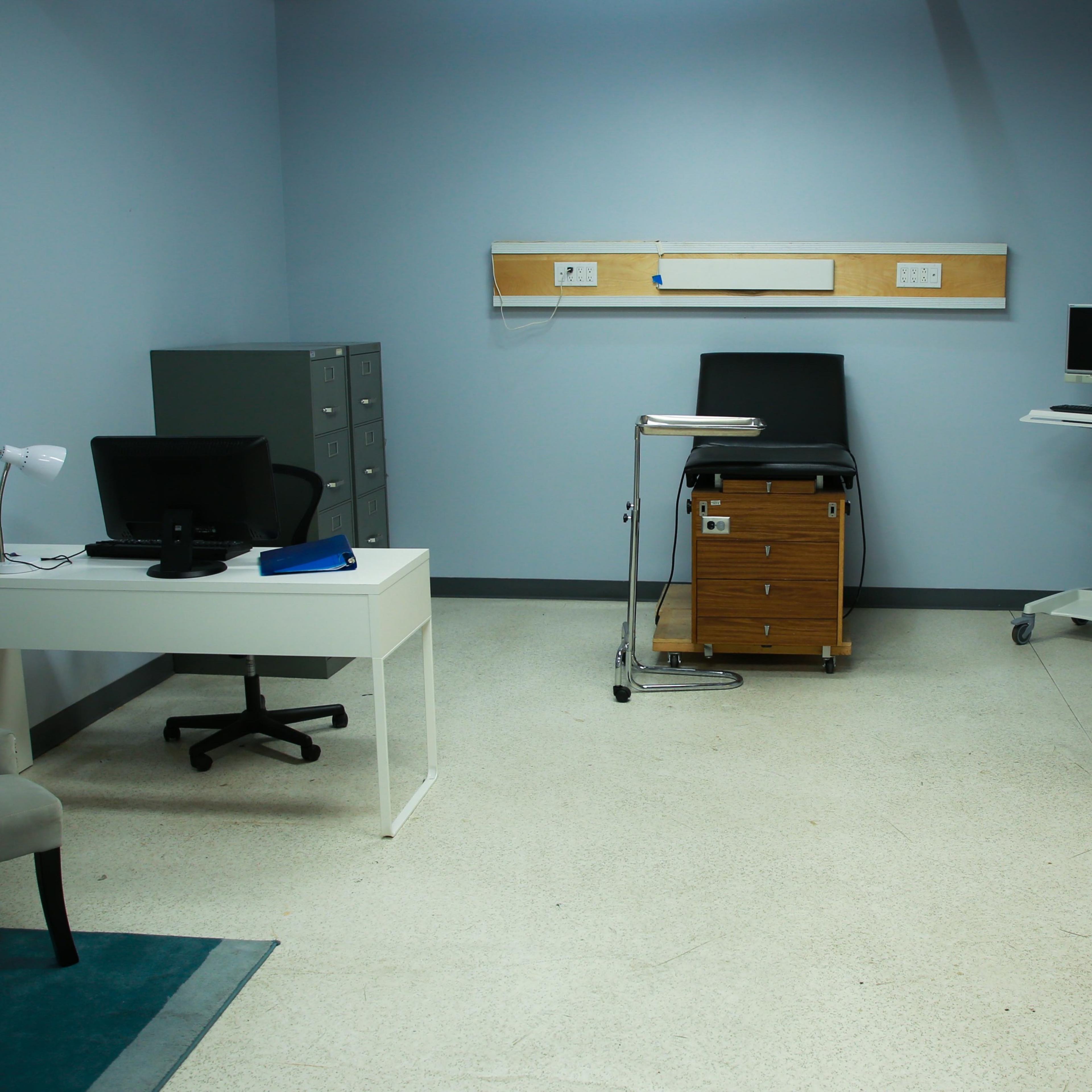 A small office space with a desk, a filing cabinet, a chair, and a computer setup against a light blue wall.