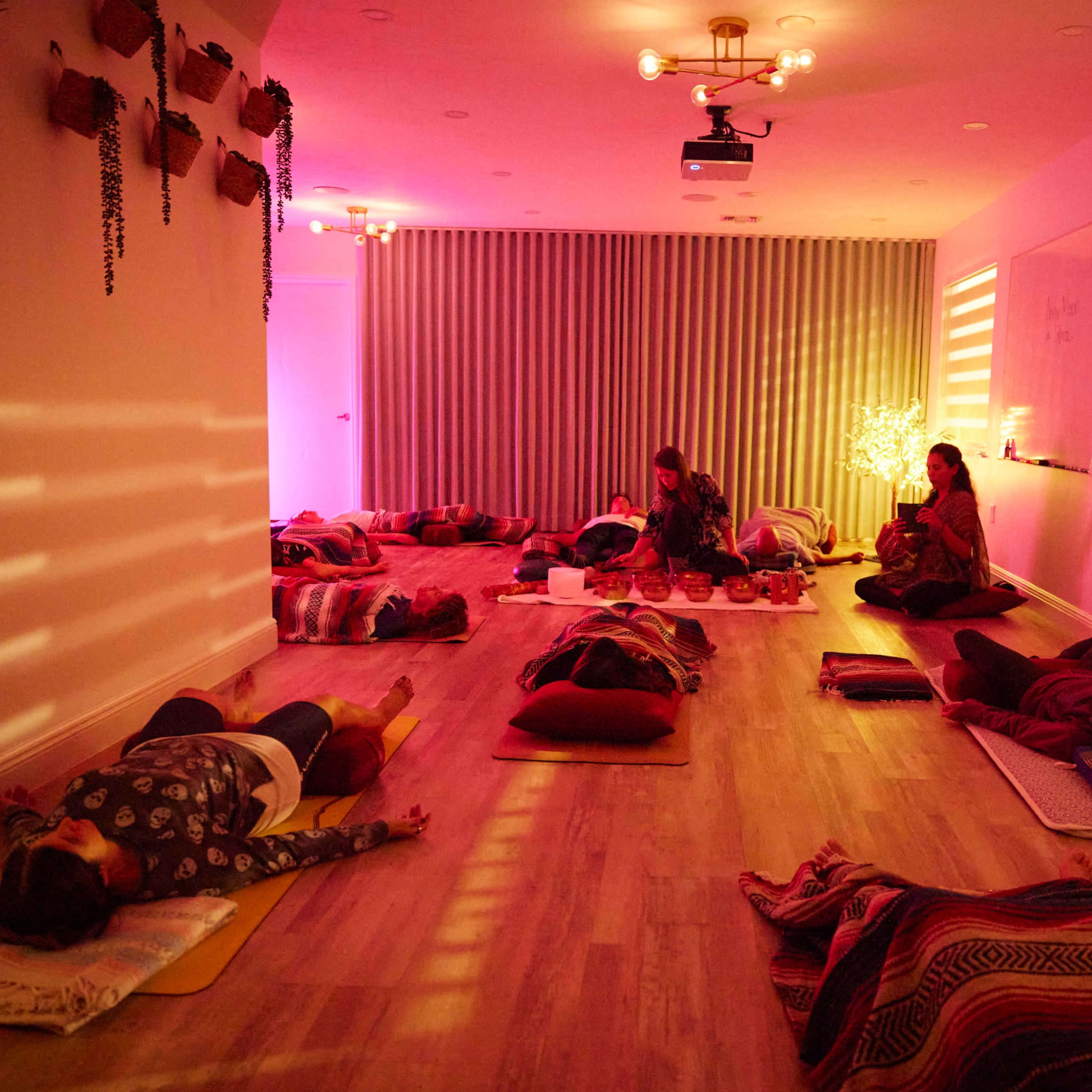 A tranquil yoga studio filled with people practicing relaxation on mats, with soft lighting and decorative walls.