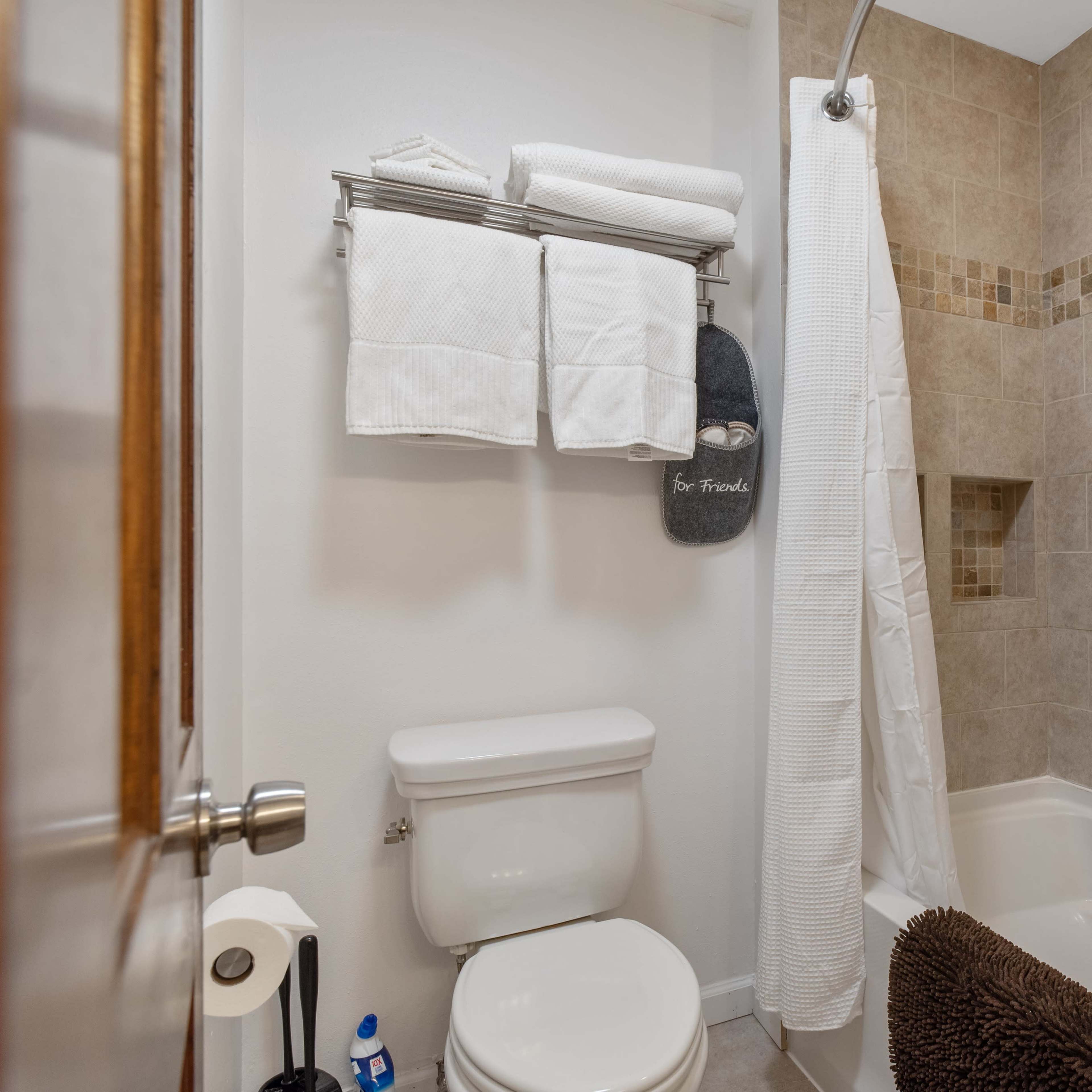 A small bathroom with a toilet, bathtub, and neatly arranged towels on a rack.