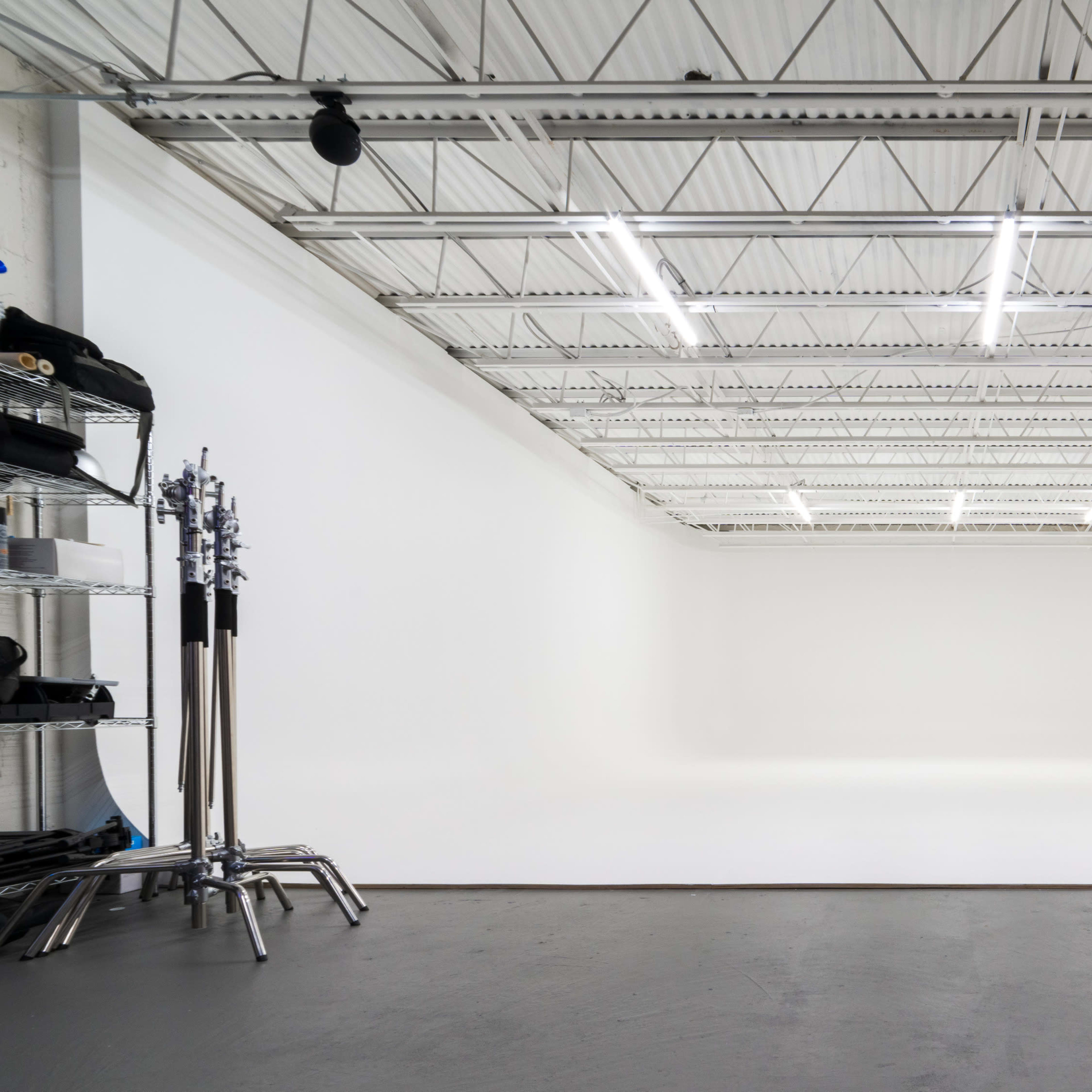 An empty photography studio with a large white backdrop and overhead lighting.