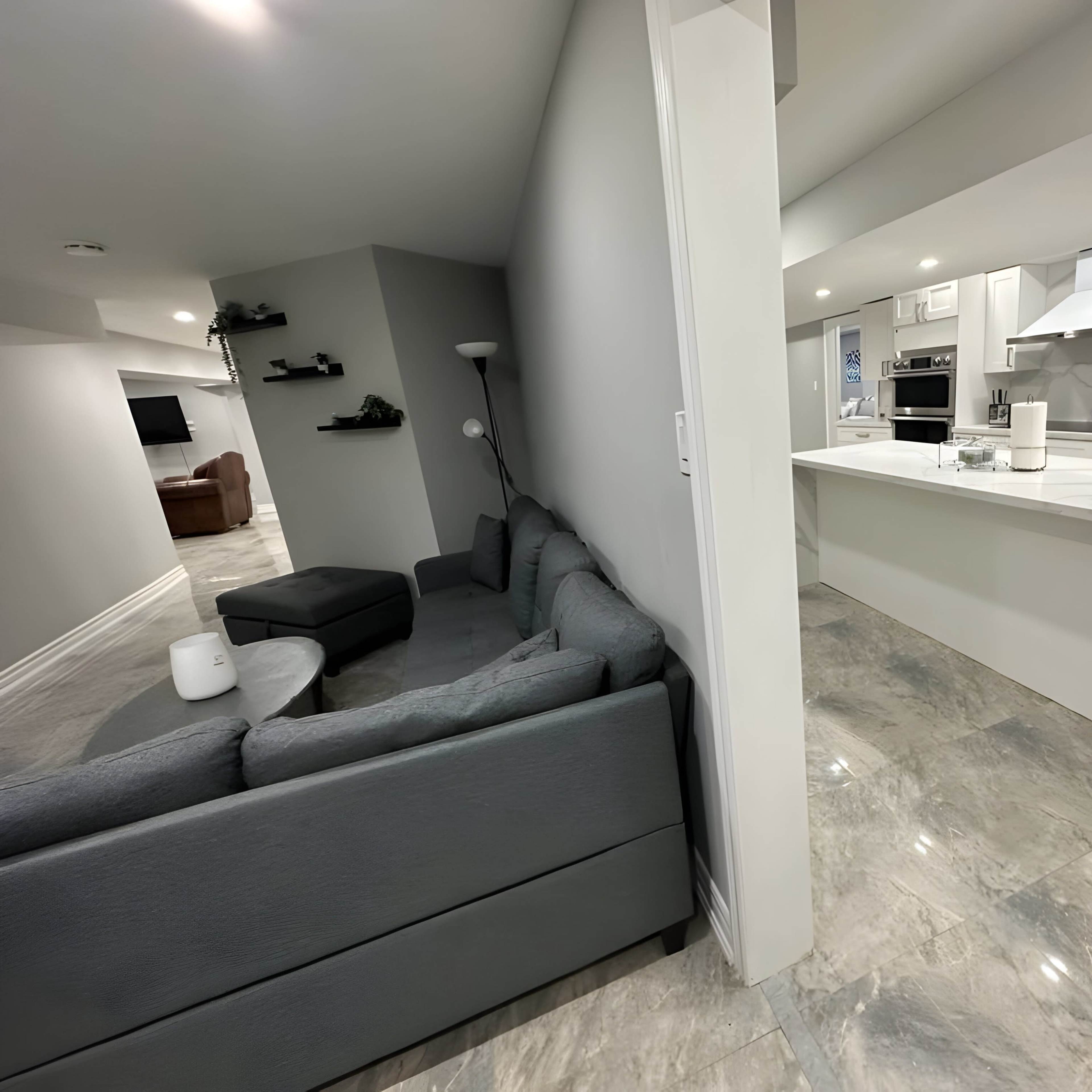 A spacious modern kitchen adjacent to a living area featuring a gray couch and minimalist decor.