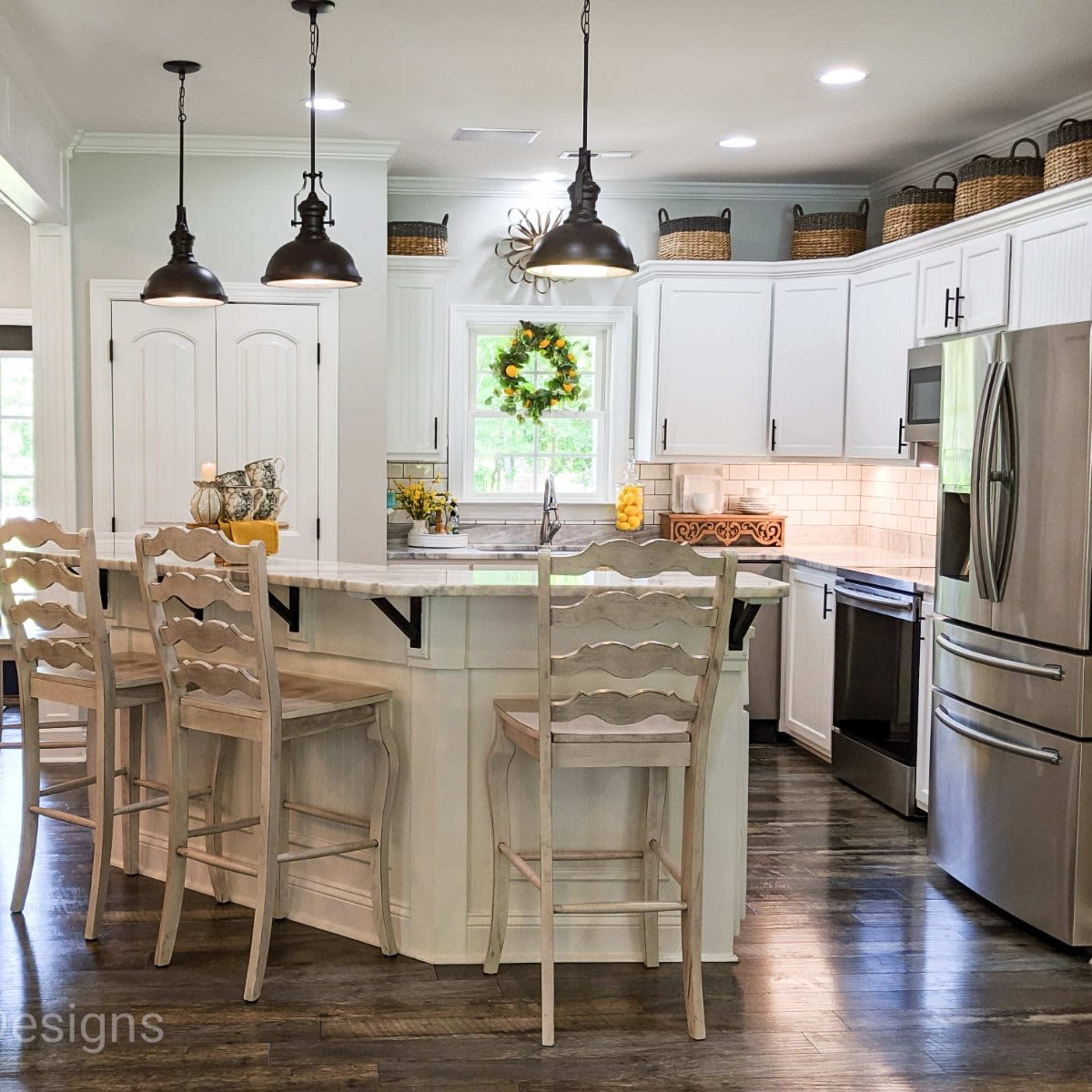 A modern kitchen features white cabinetry, stainless steel appliances, and a large island with seating.