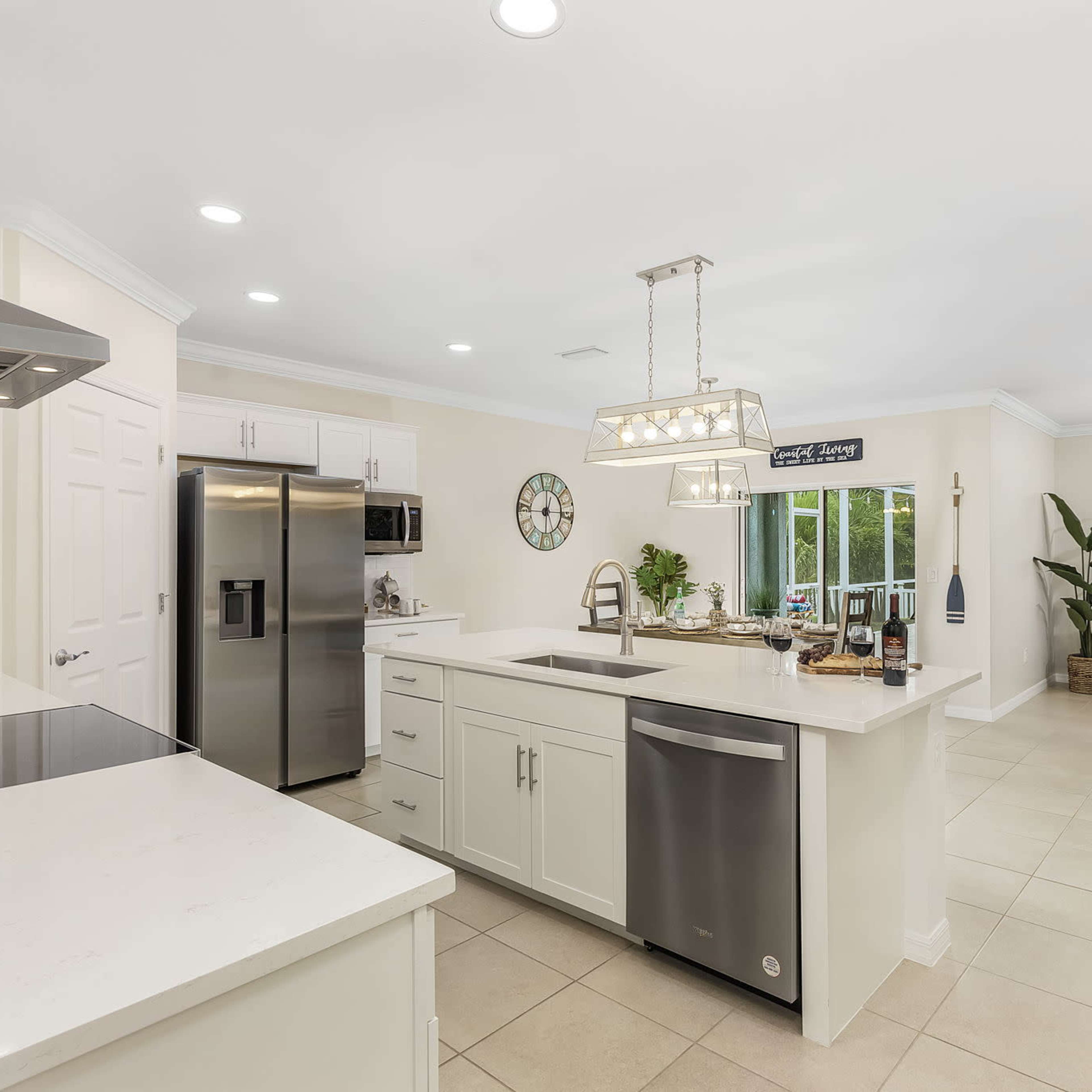 A modern kitchen with stainless steel appliances, white cabinetry, and a spacious seating area visible in the background.