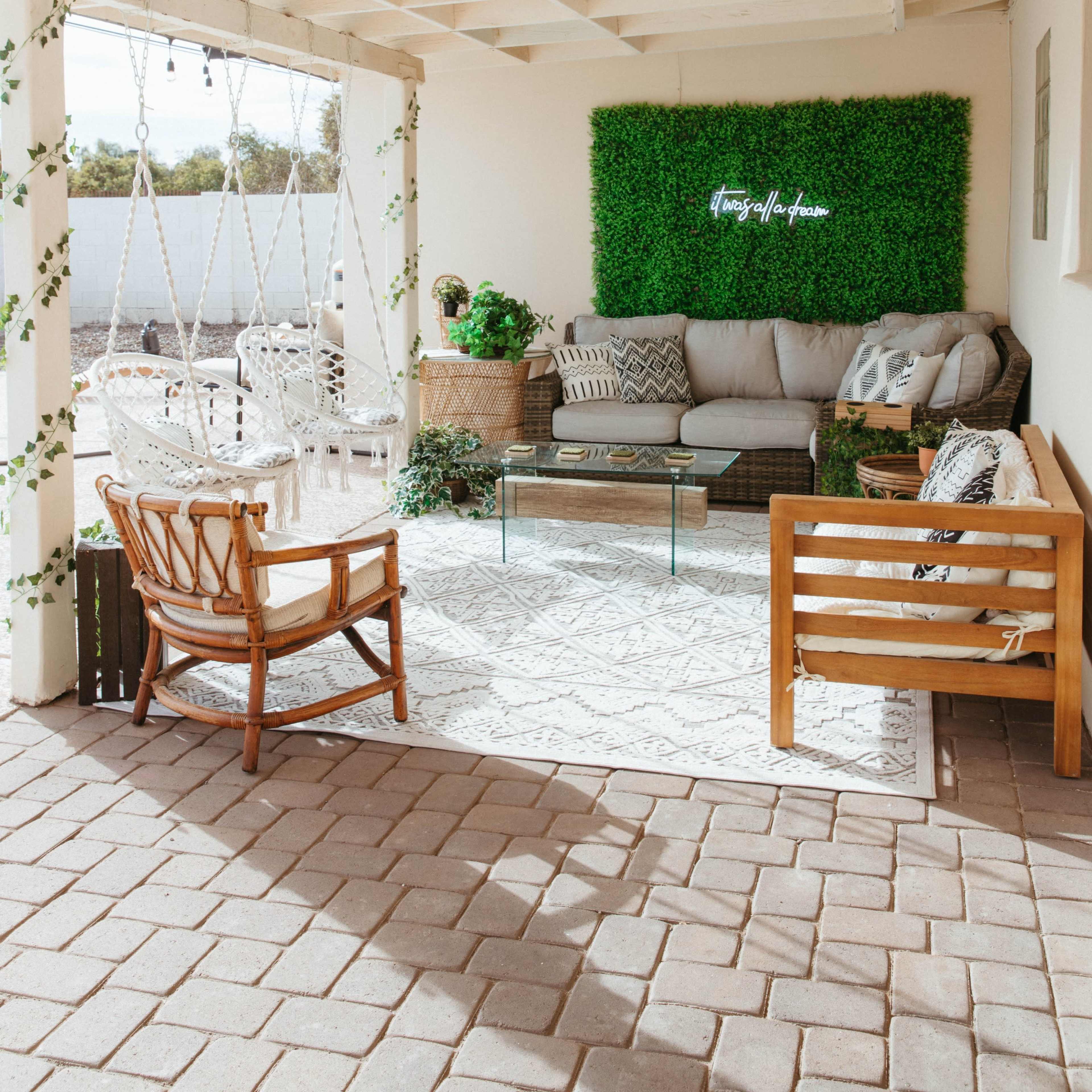 A cozy outdoor seating area with a green wall, comfortable furniture, and decorative plants.
