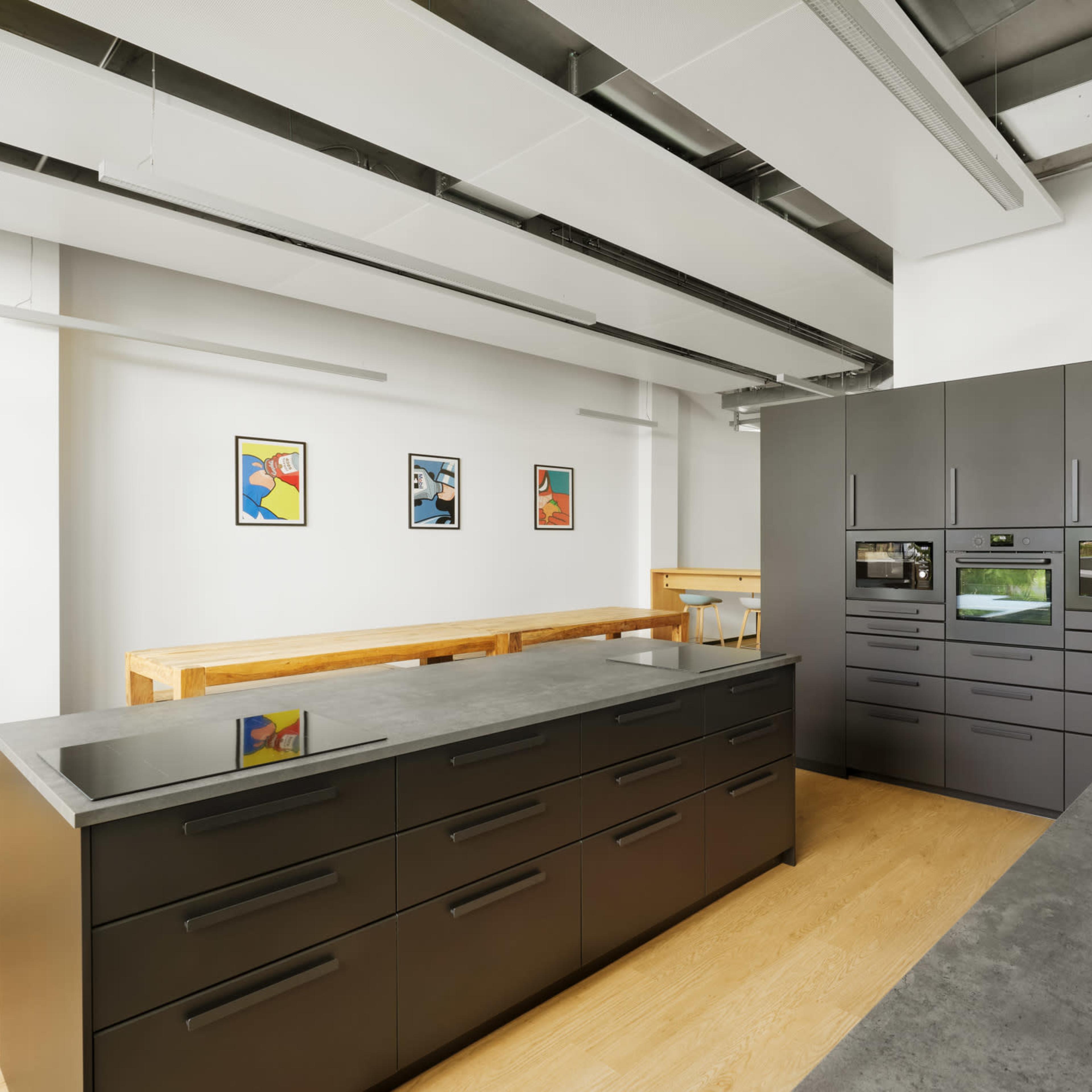 A modern kitchen with a large central island, dark cabinetry, built-in appliances, and minimalist decor.