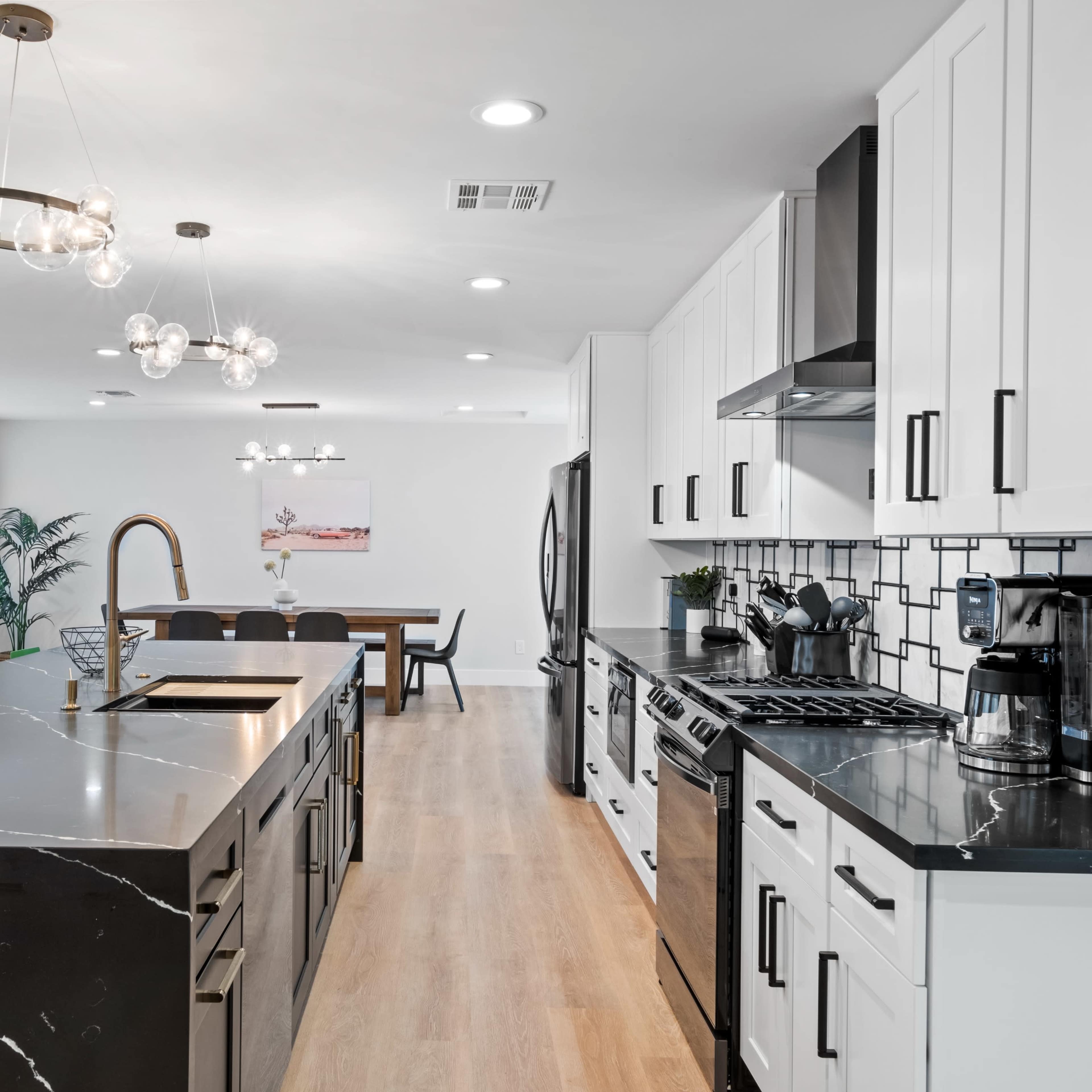 A modern kitchen featuring a large island with a black countertop, white cabinetry, and stainless steel appliances.