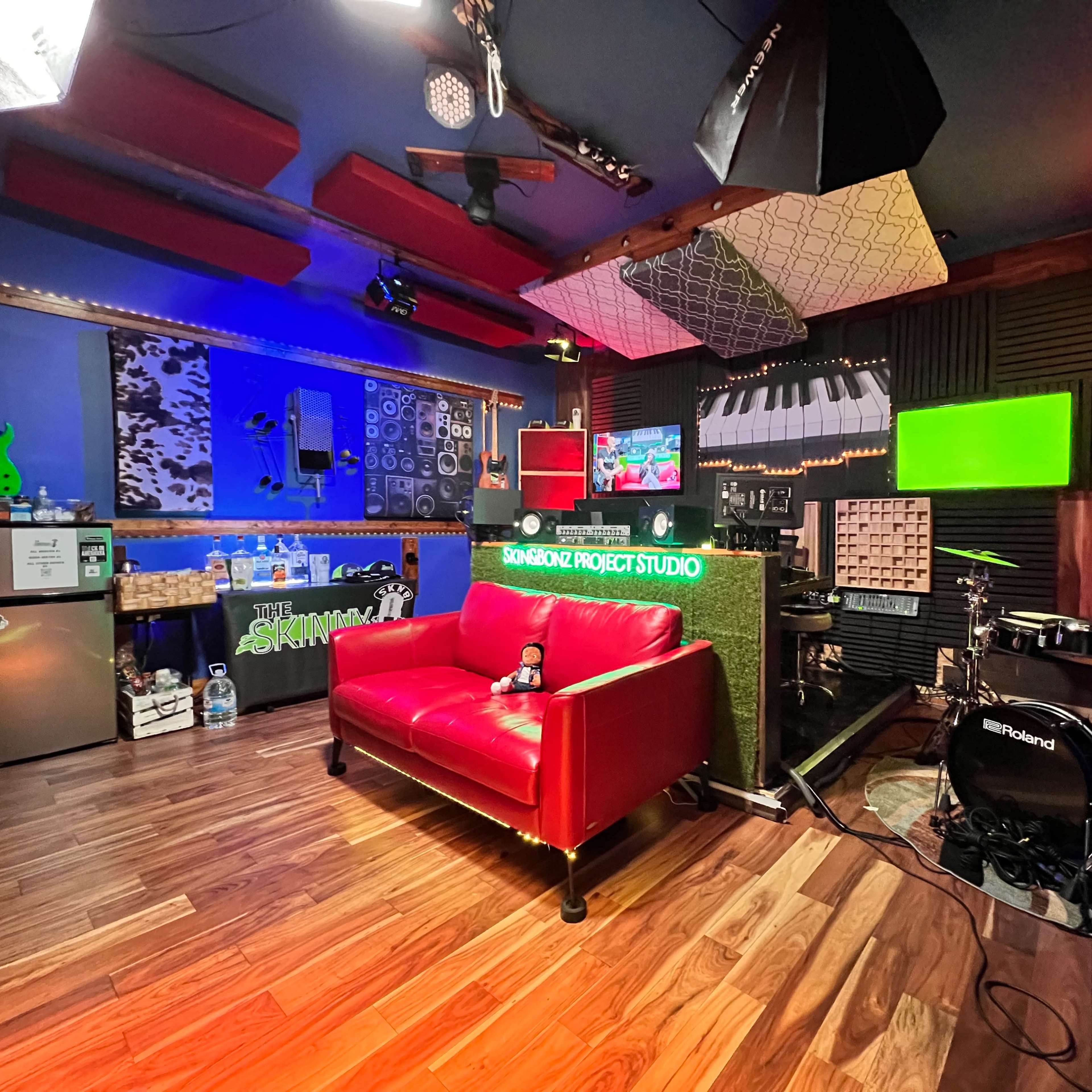 A vibrant music studio with a red sofa, various musical instruments, colorful decor, and soundproofed walls.