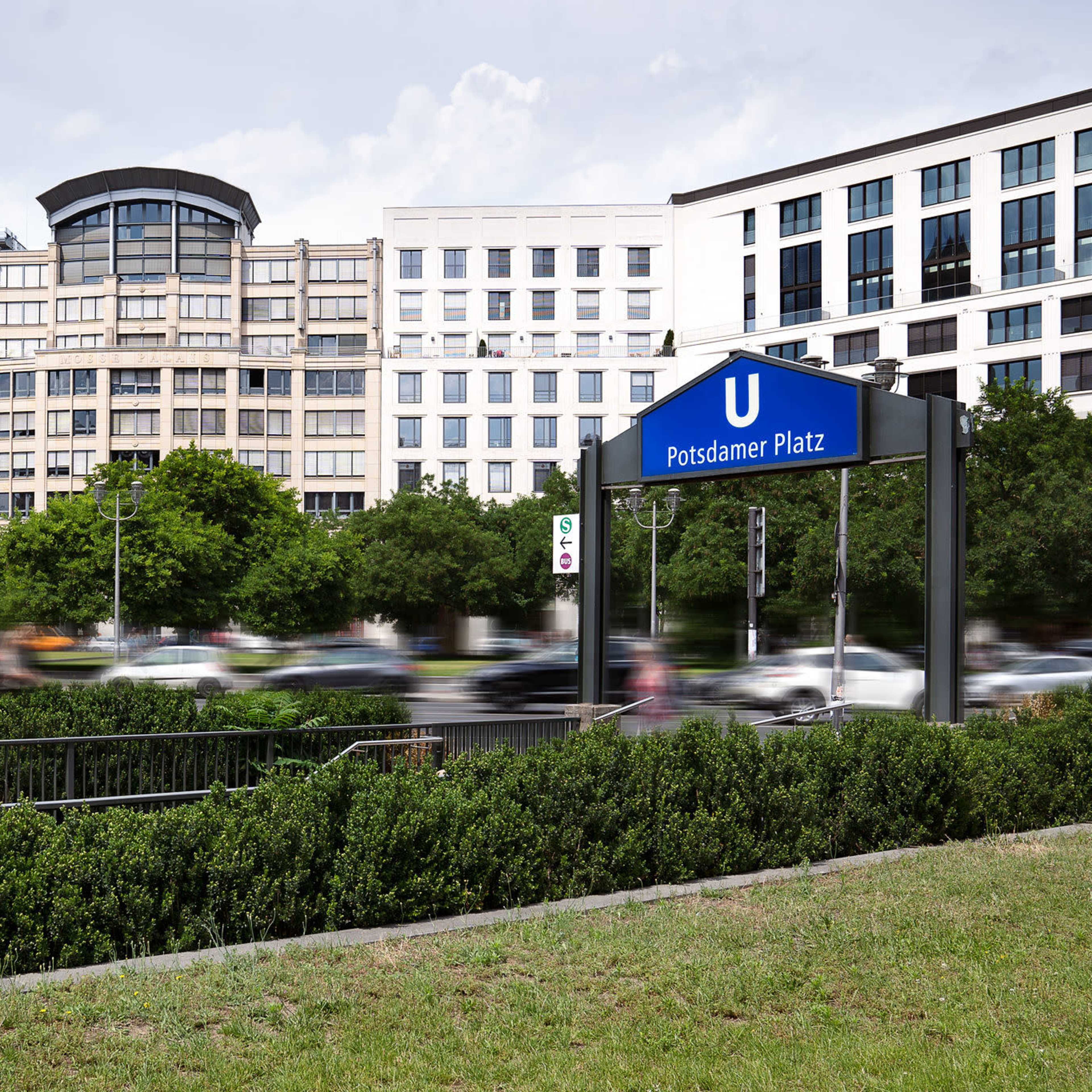 The U-Bahn station sign at Potsdamer Platz, with modern buildings and traffic in the background.