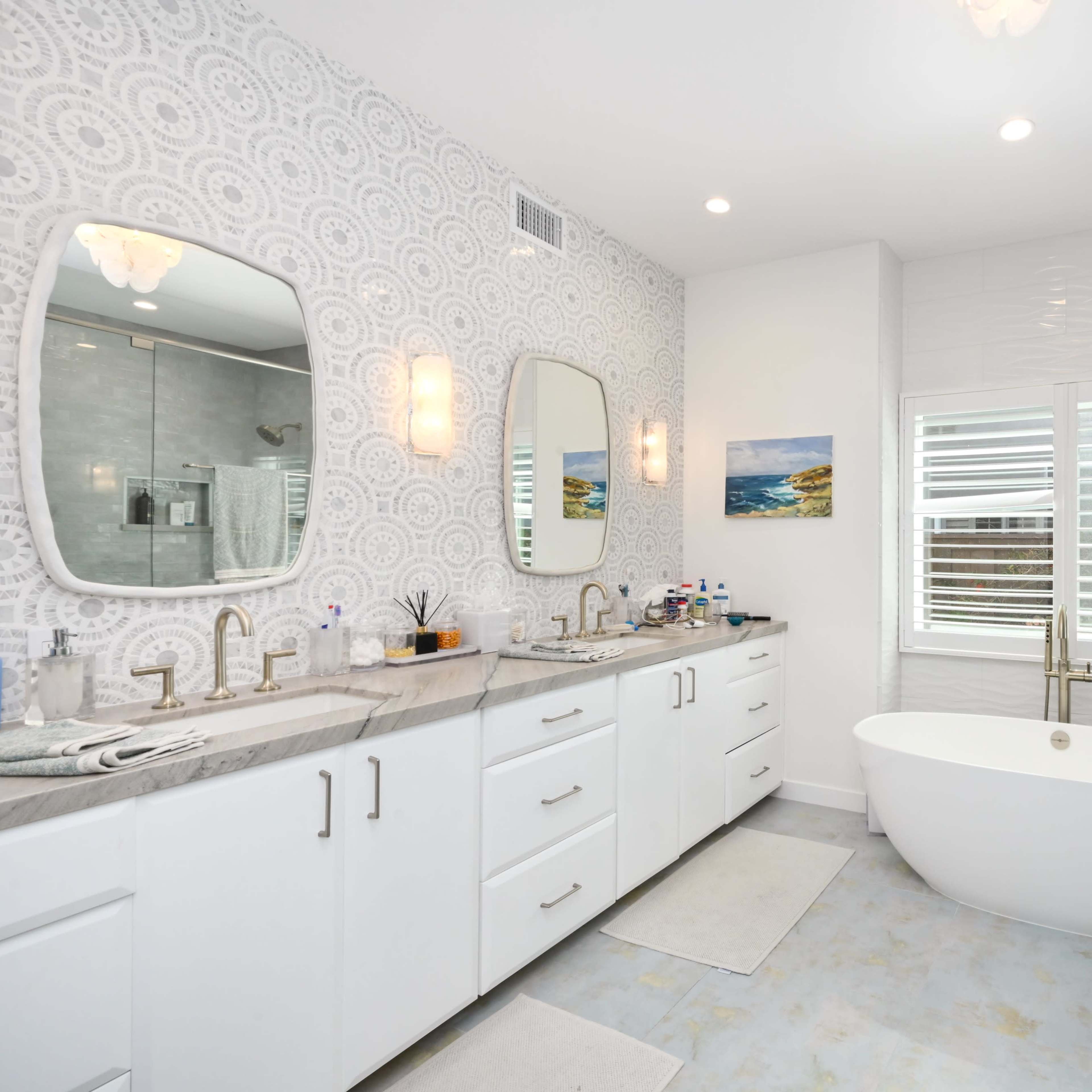 A modern bathroom featuring a freestanding bathtub, dual sinks with mirrors, and a glass-enclosed shower.