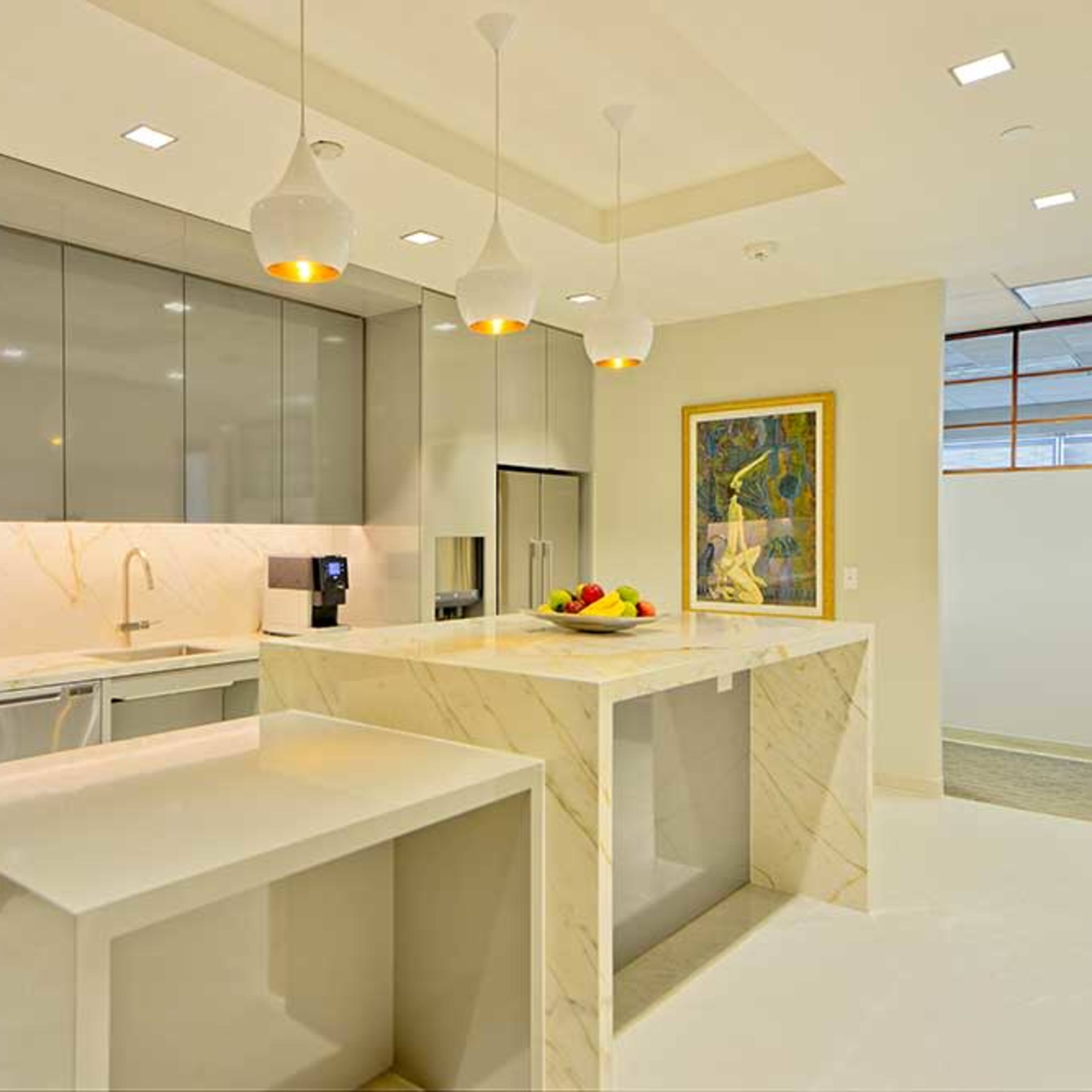 A modern kitchen featuring sleek cabinets, a large island with a marble countertop, and pendant lighting above.
