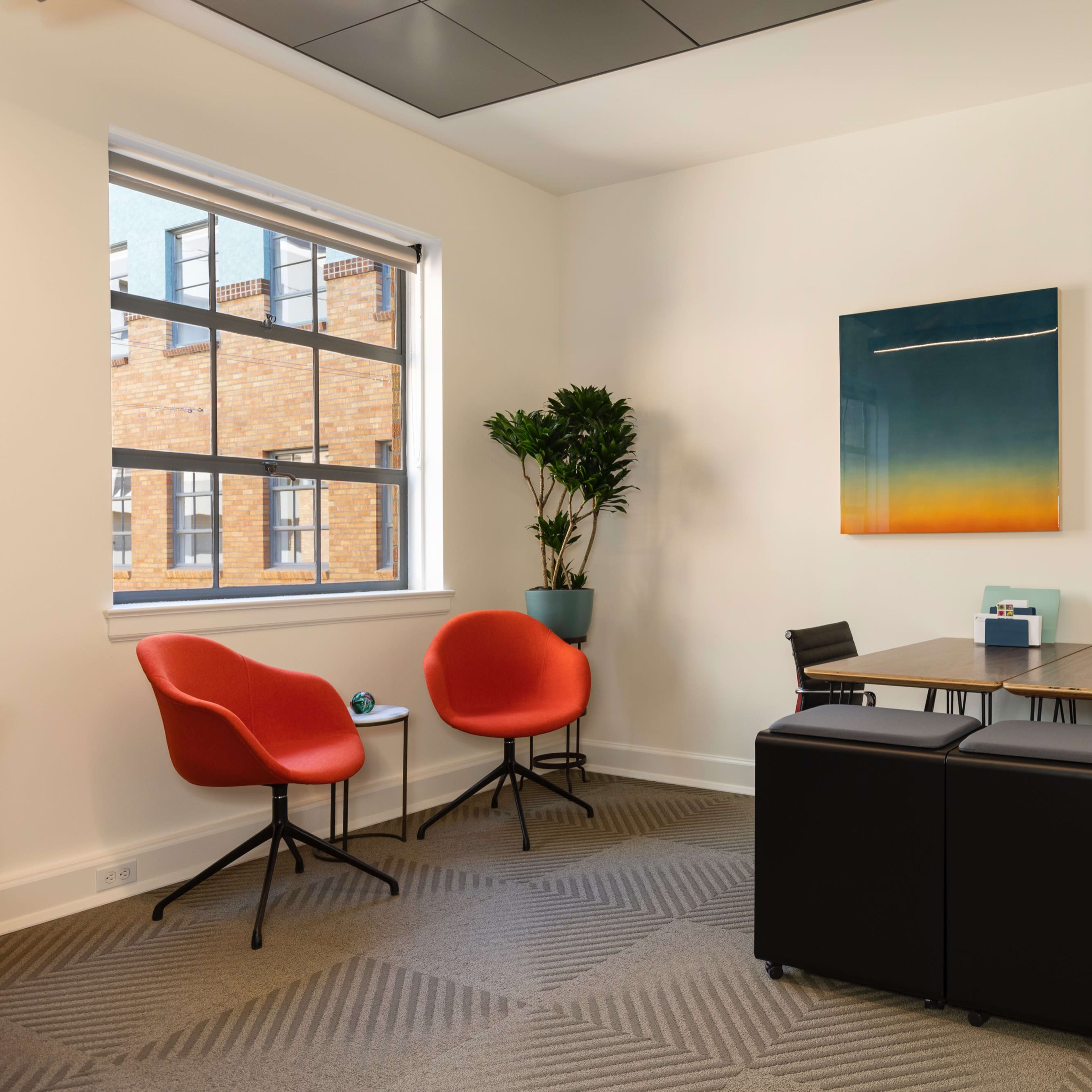 A small meeting room with a table, chairs, and a large window letting in natural light.