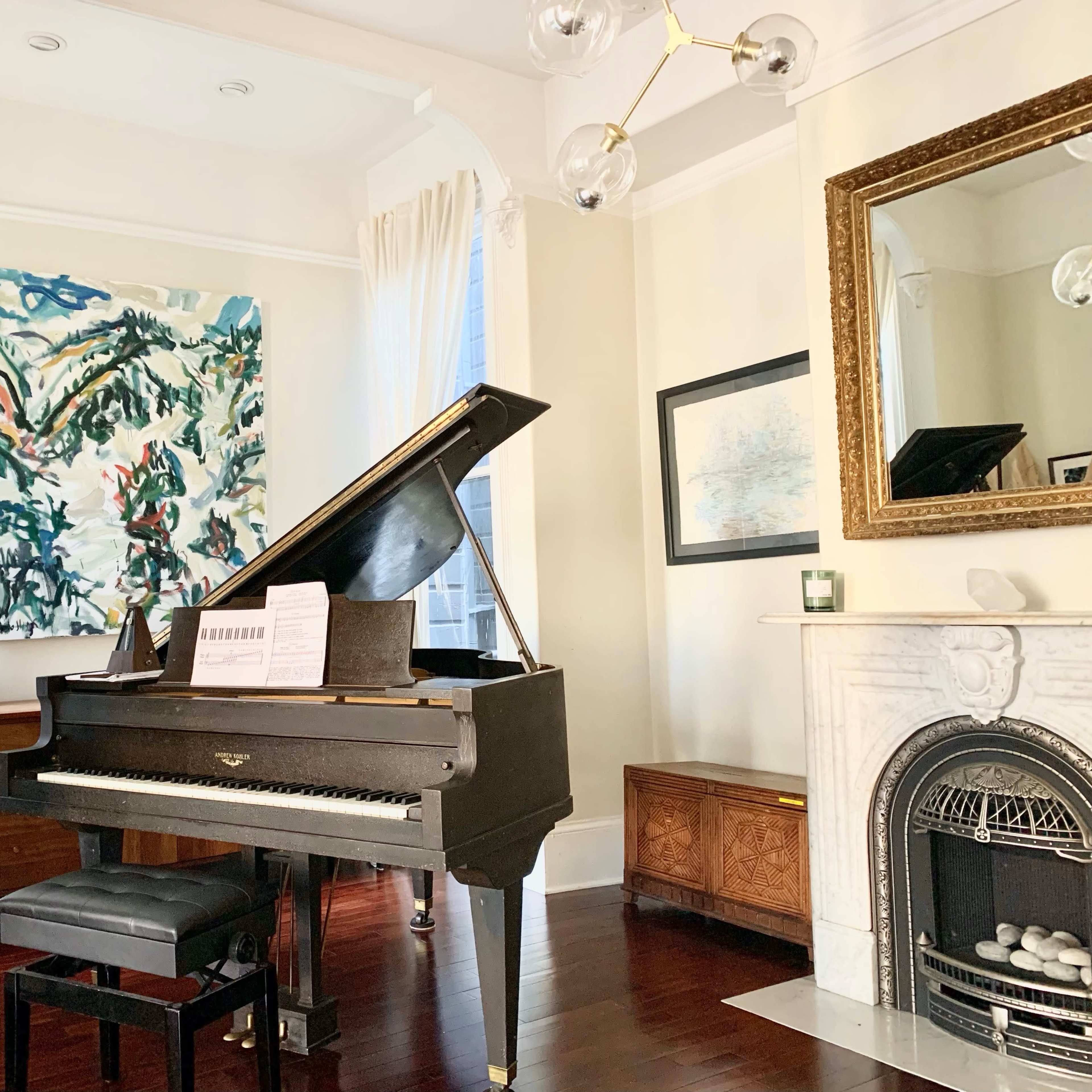 A grand piano positioned in a well-lit corner of a room, complemented by a large abstract painting and elegant furniture.