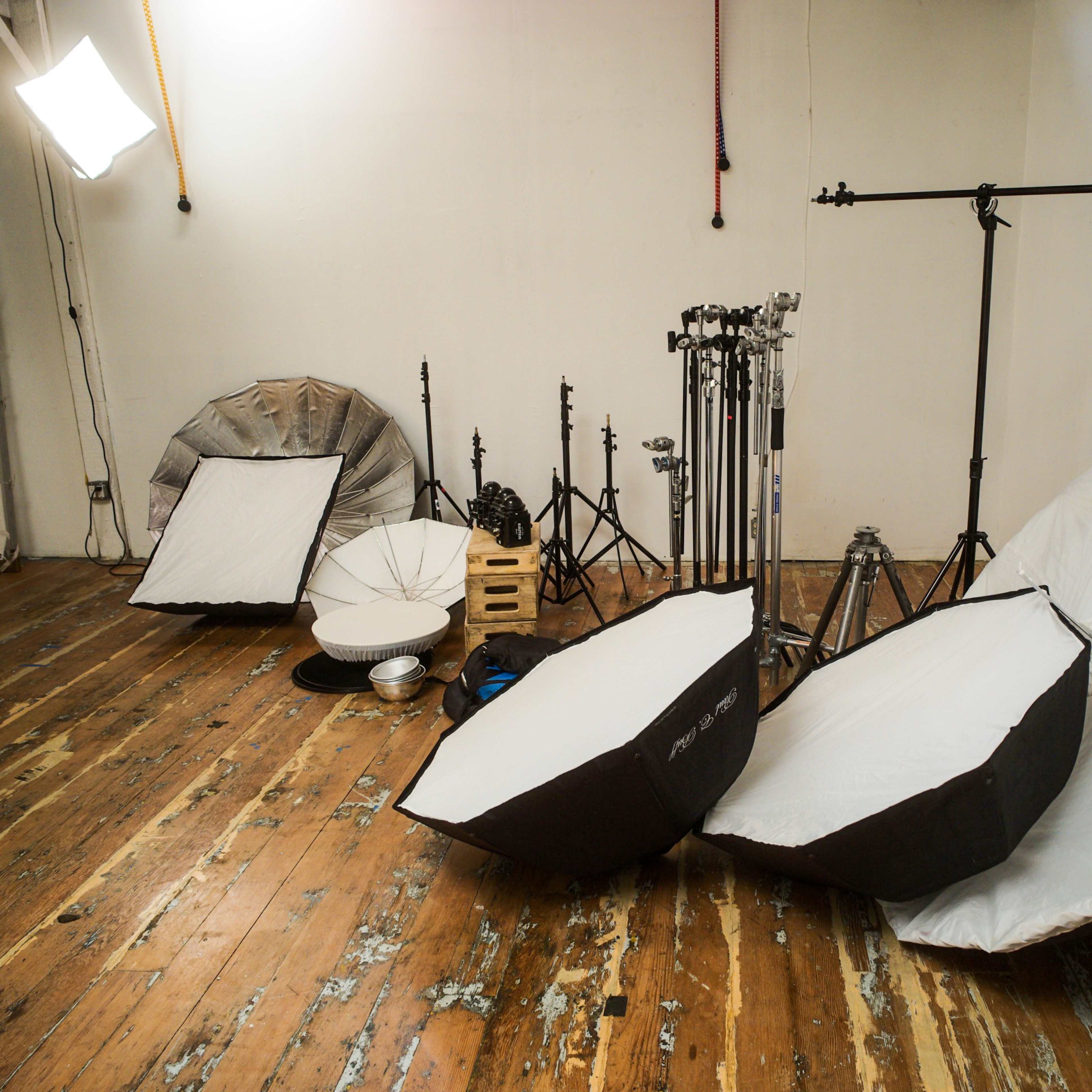 A photography studio with several light umbrellas, stands, and wooden flooring.