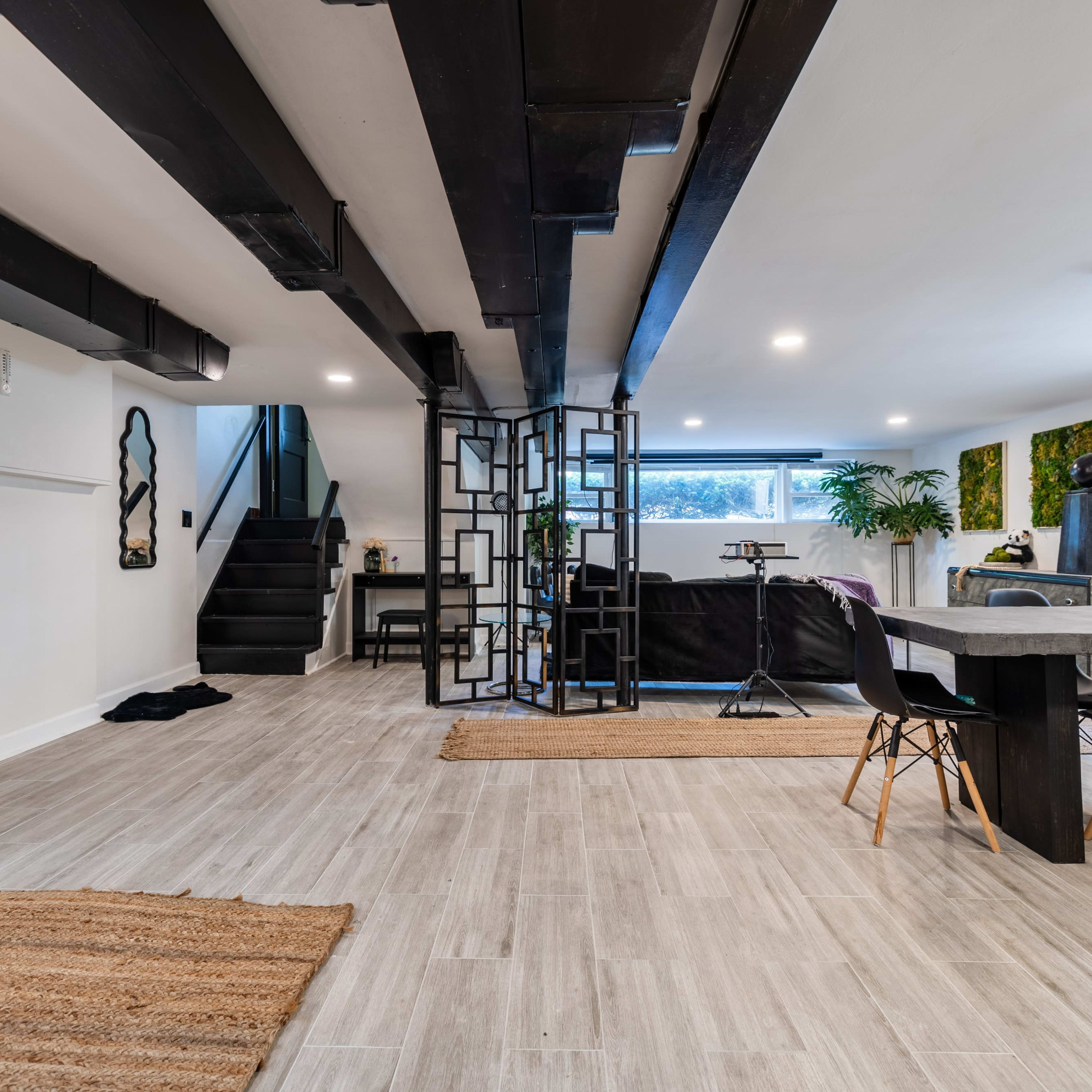 A modern interior space featuring a dining area with a table and chairs, a staircase in the background, and decorative wall art.