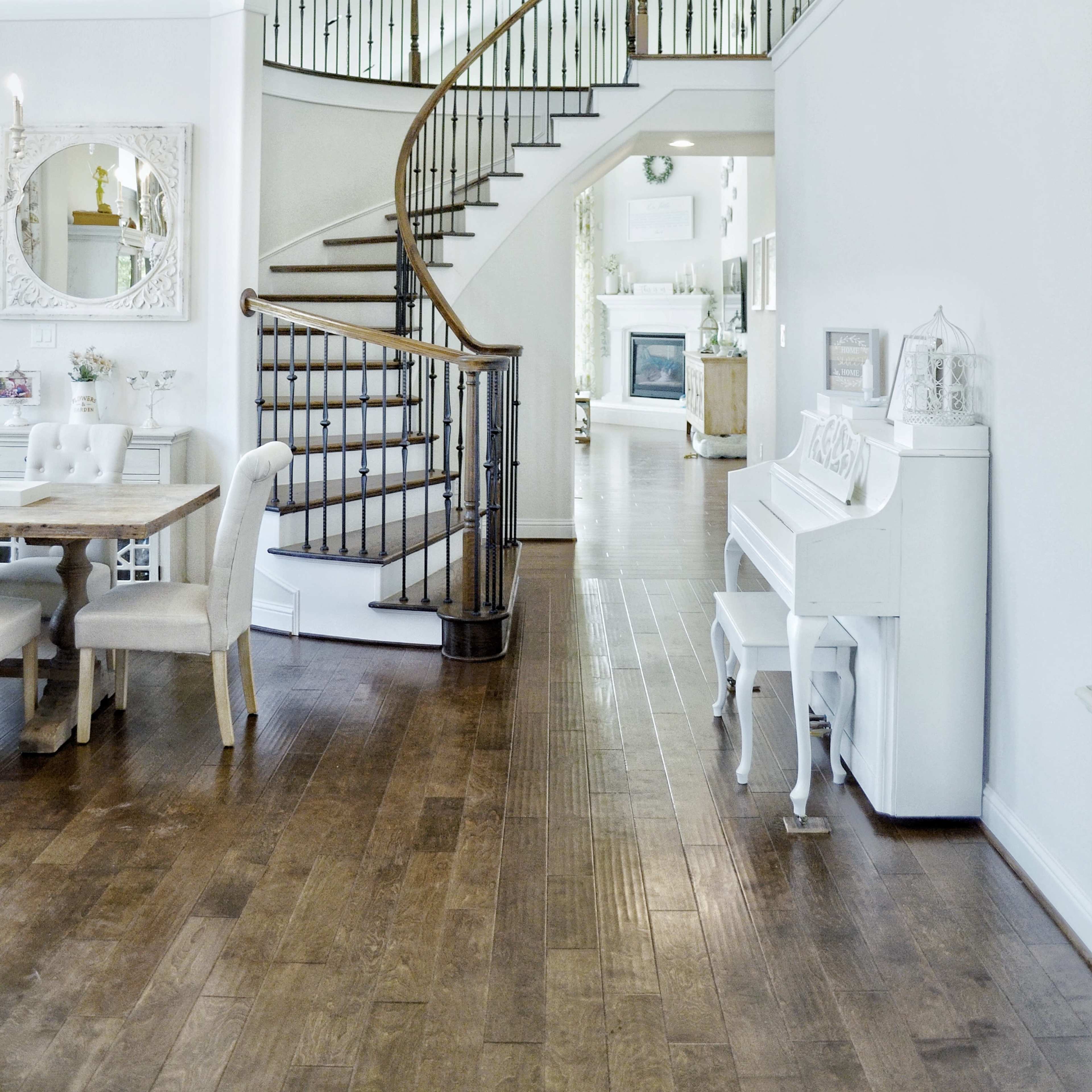 A modern interior with a curved staircase leading to an upper level, adjacent to a dining area and a living room in the background.