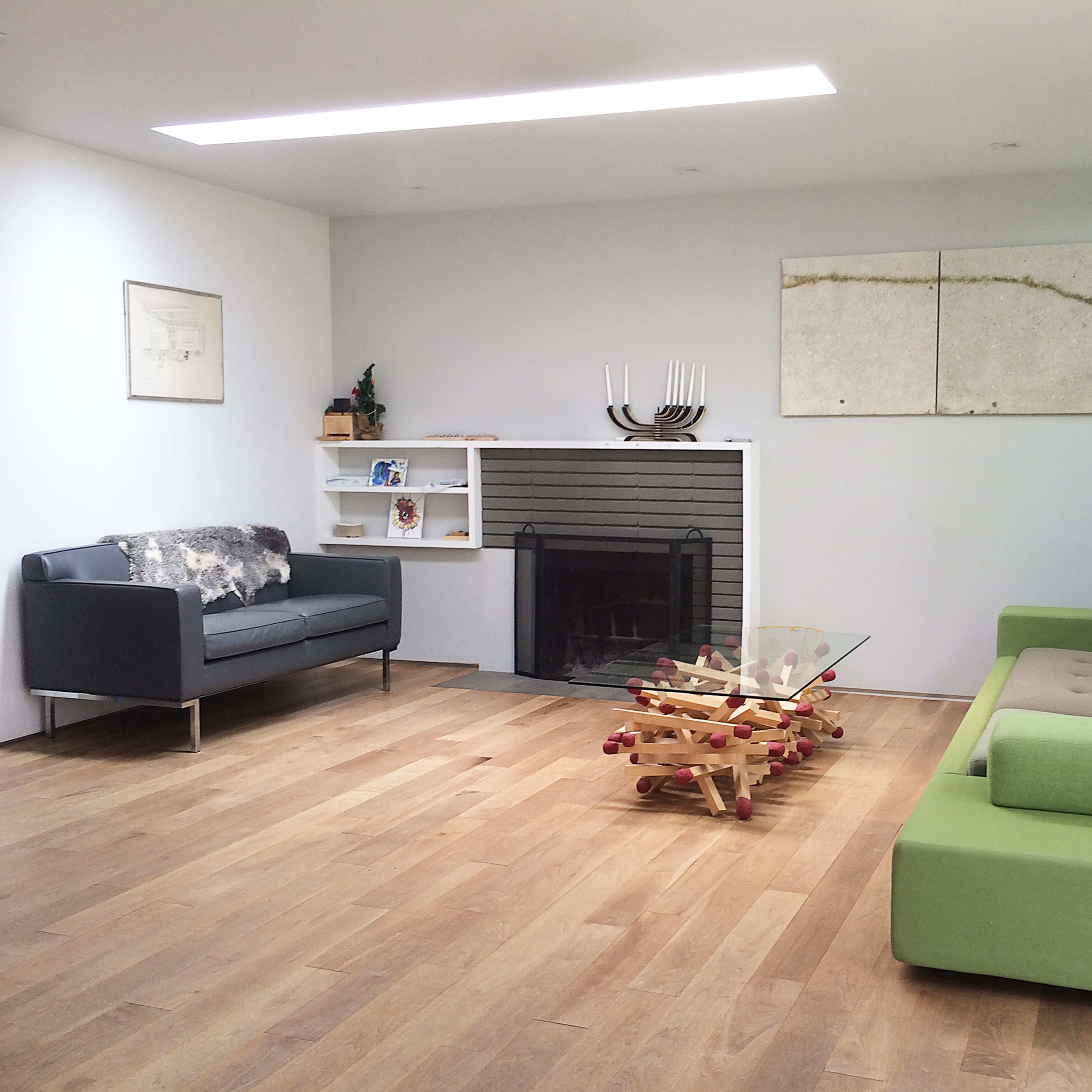 A modern living room featuring two sofas, a wooden floor, a glass coffee table, and abstract wall art.