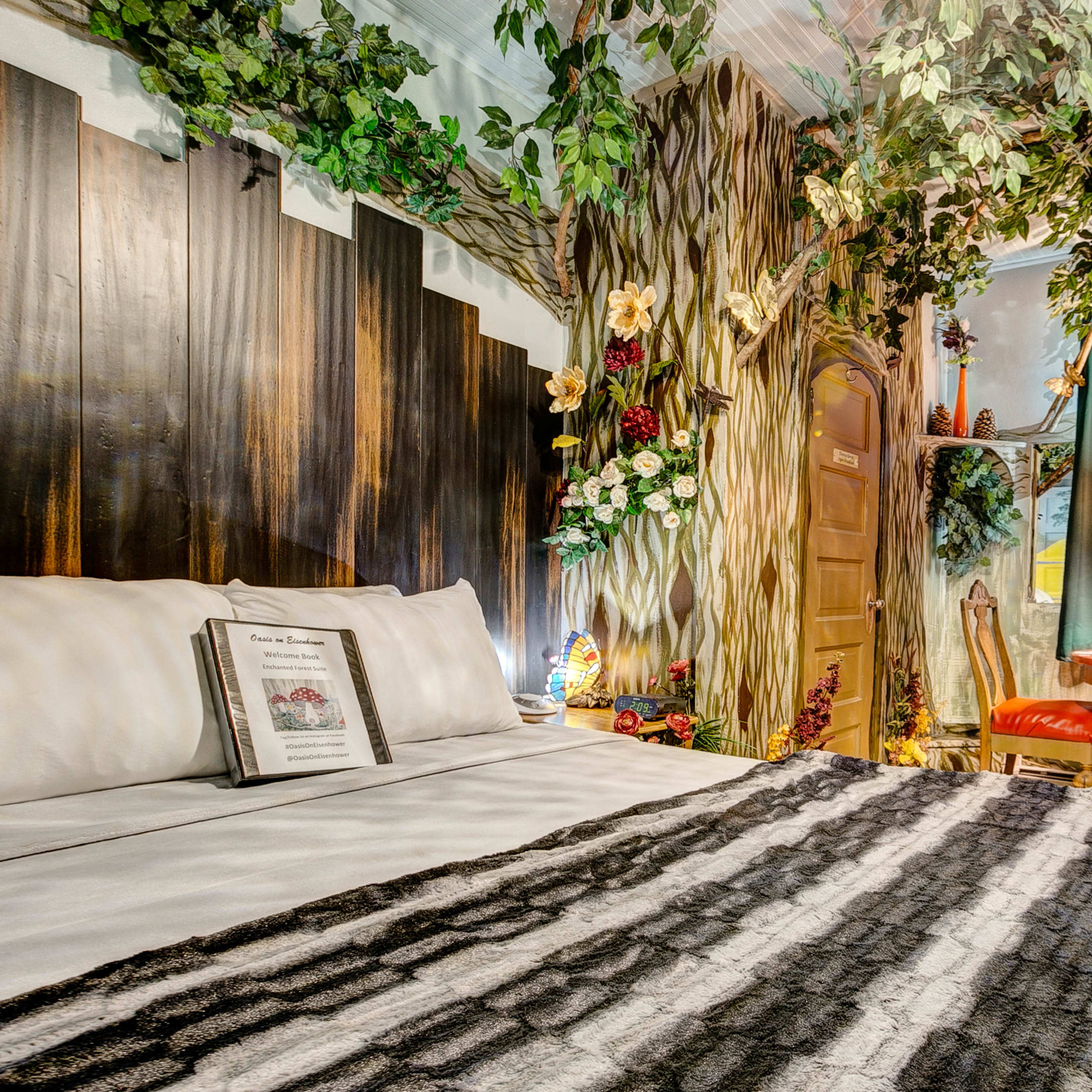 A uniquely decorated bedroom with a tree-themed mural, a wooden door, and a small dining table surrounded by chairs.