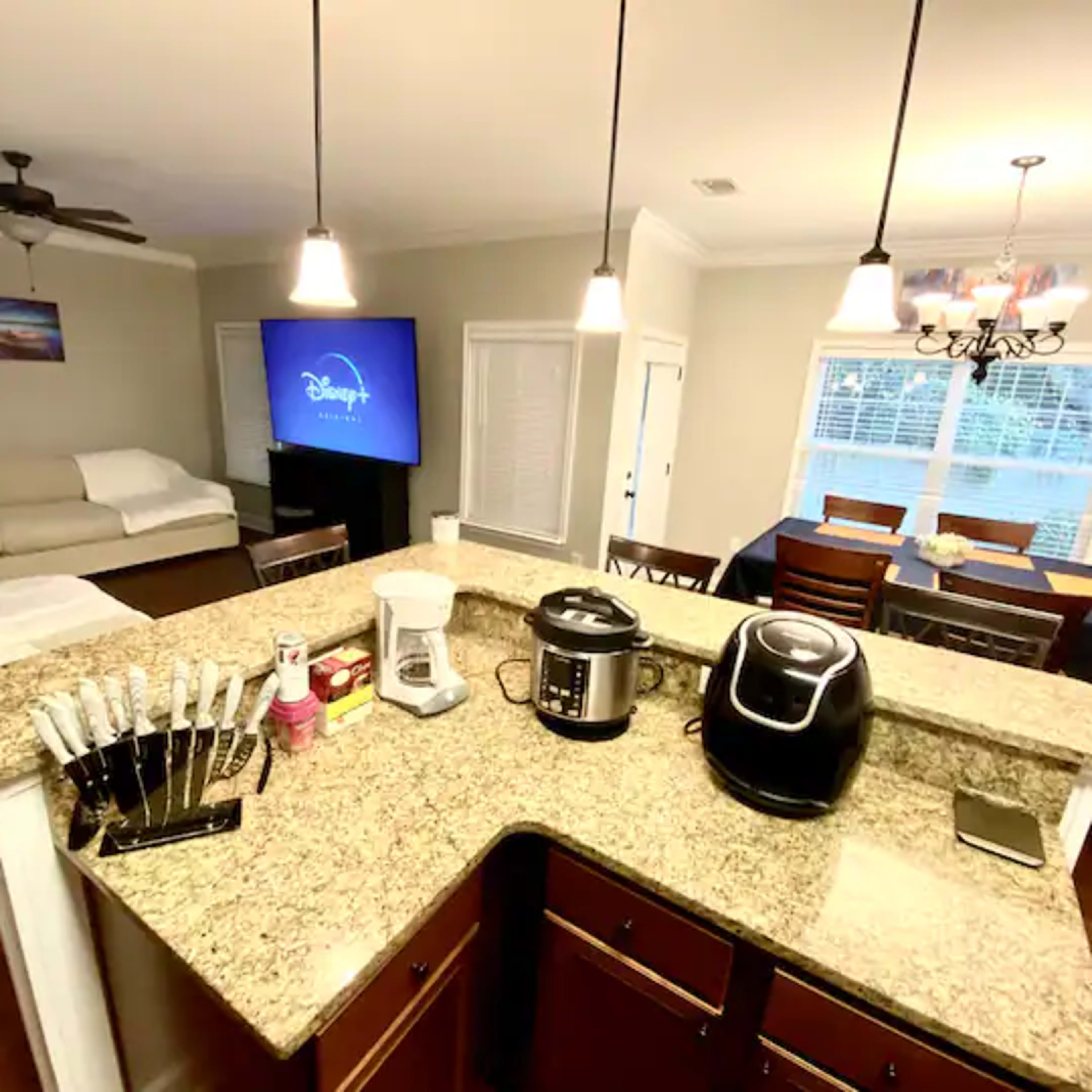 A modern kitchen with granite countertops, featuring kitchen appliances and a dining area with a table and chairs.