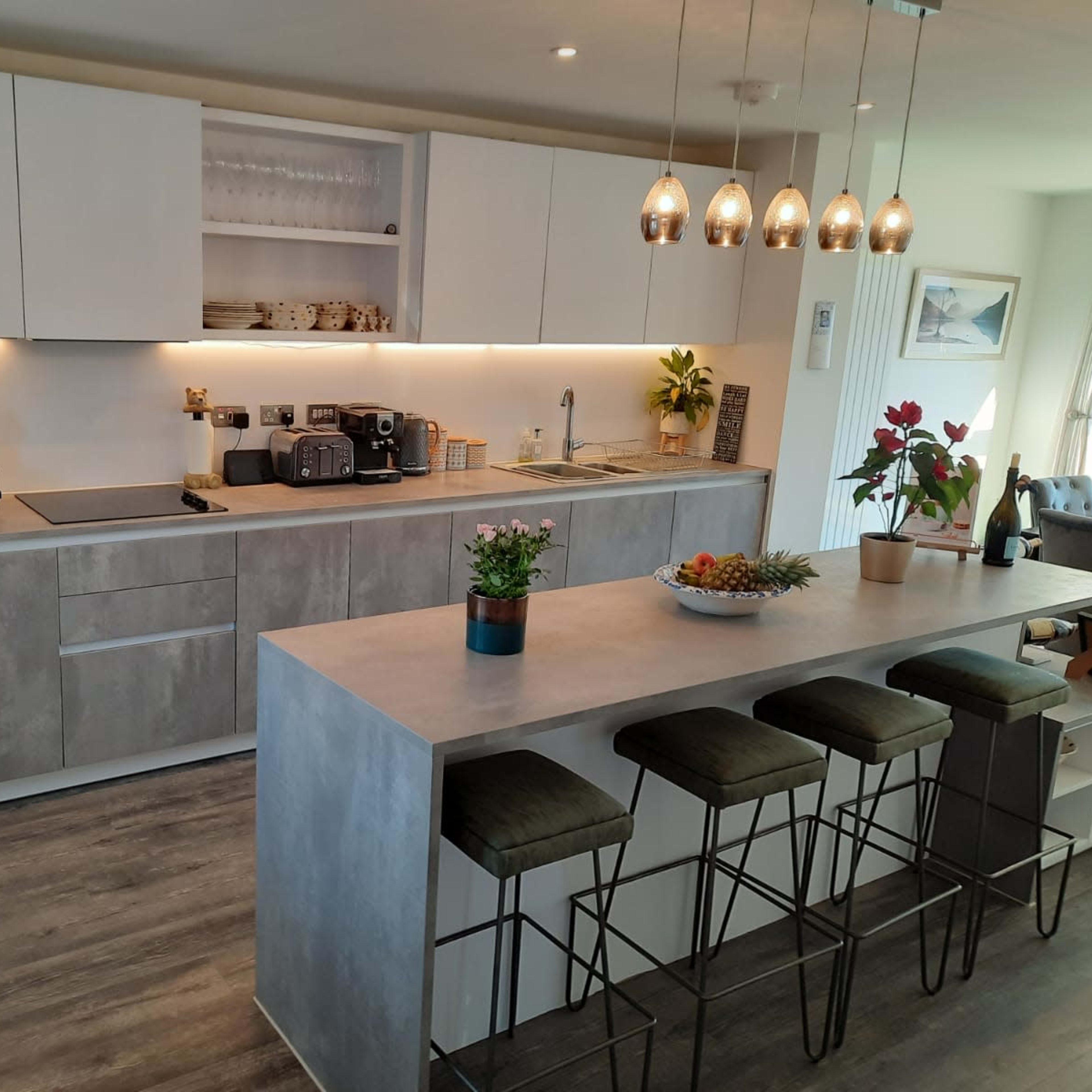 A modern kitchen with sleek cabinetry, integrated appliances, and a central island featuring bar stools.