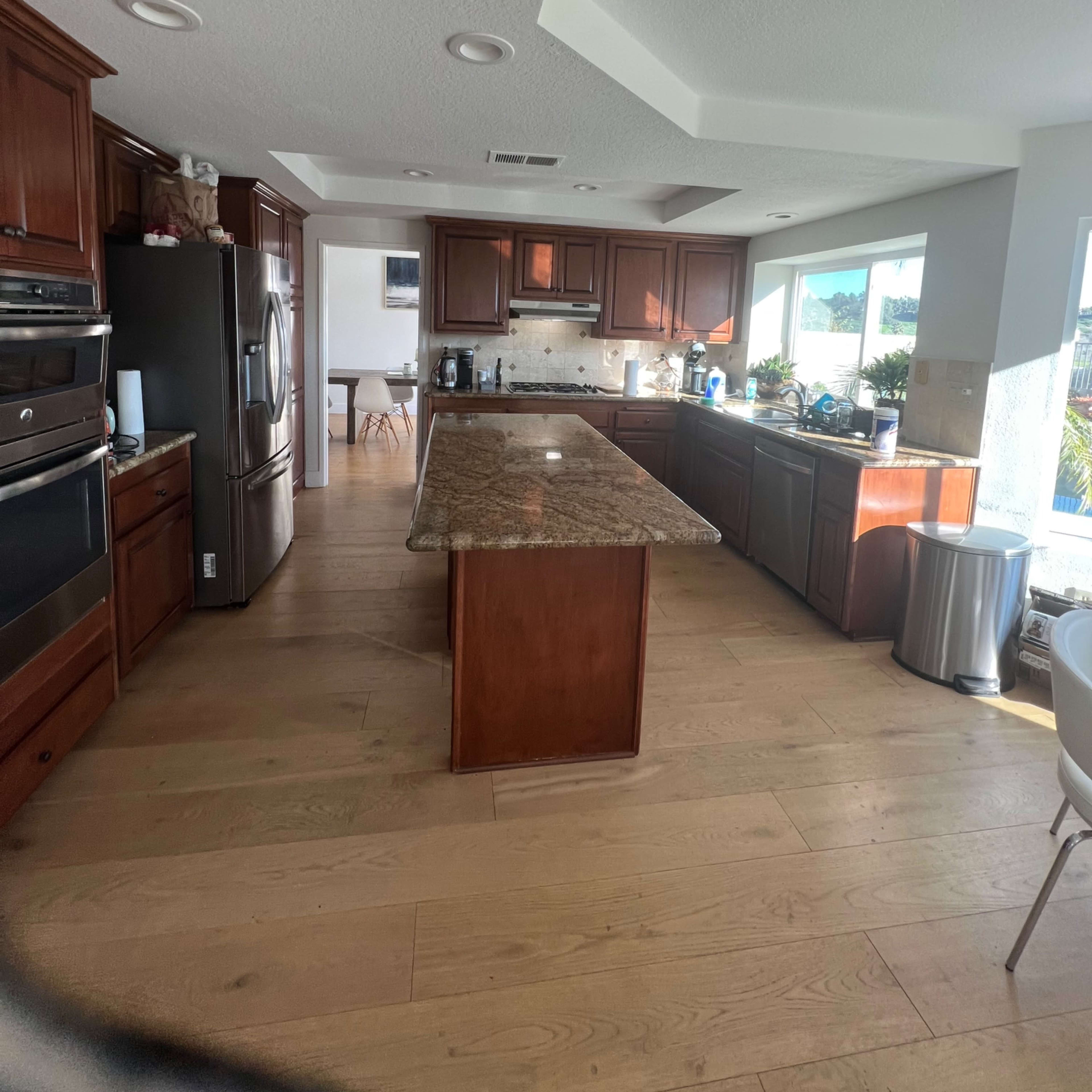 A spacious kitchen with wooden cabinets, a central island, and large windows providing natural light.