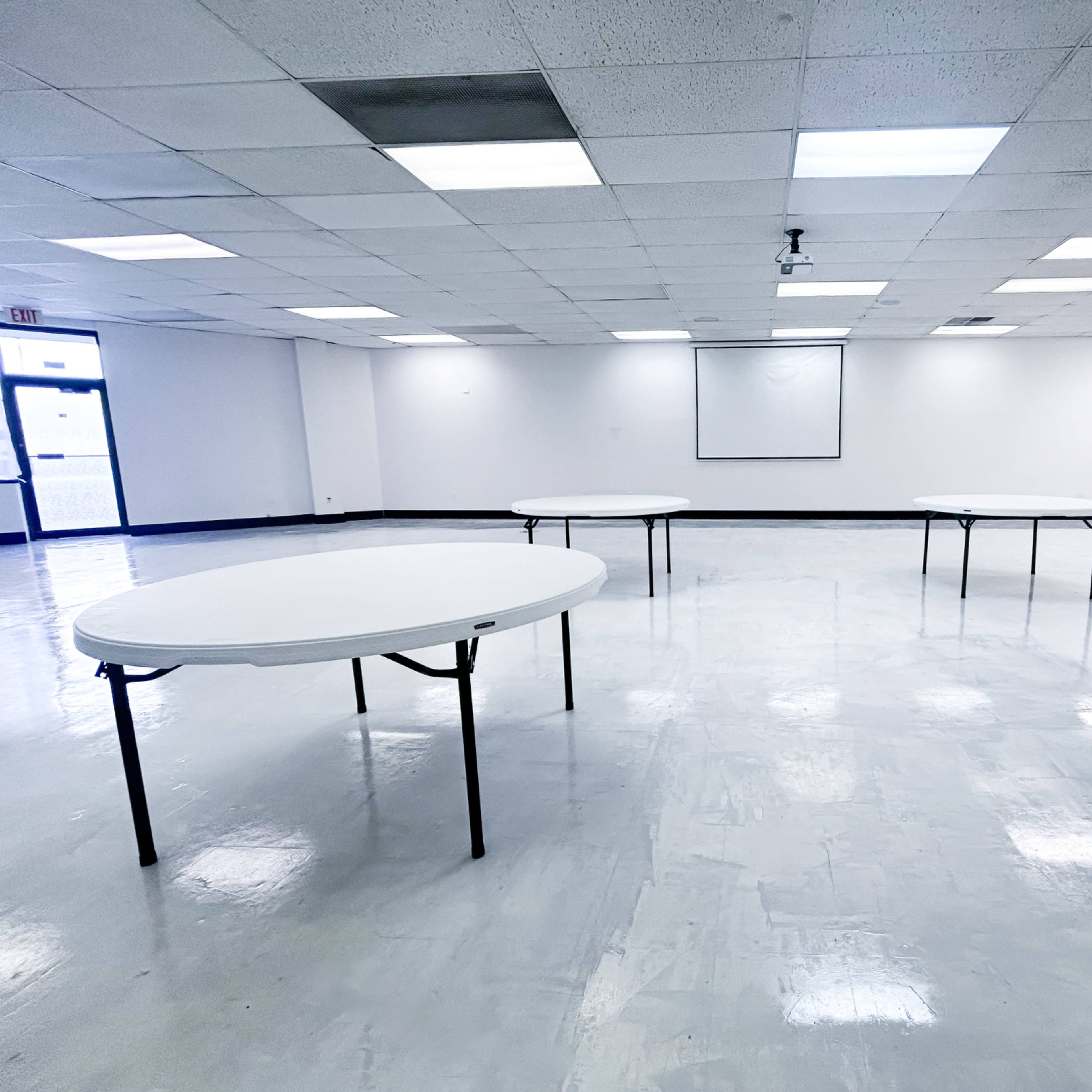 A large, empty room with several round tables arranged in a spacious, well-lit area.