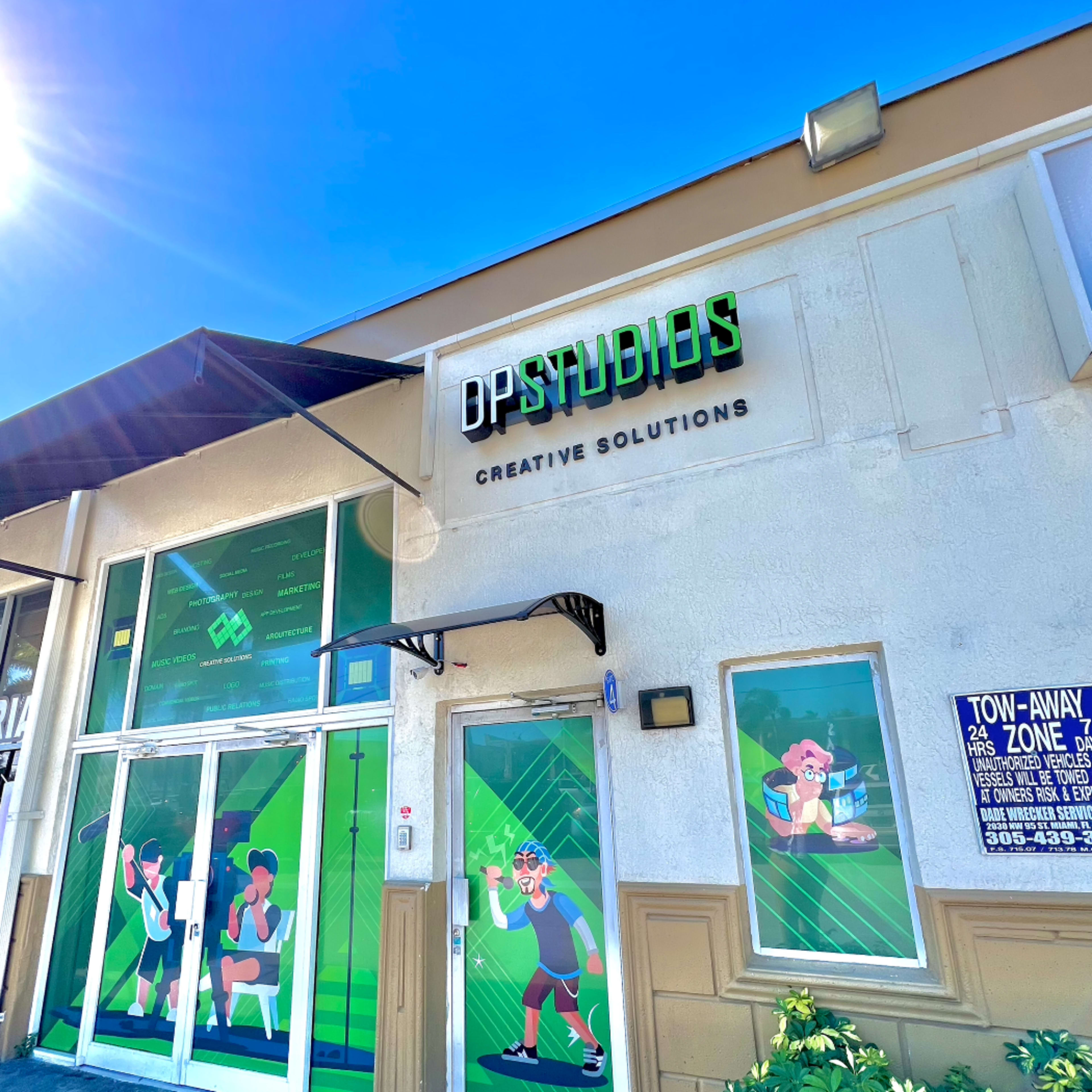 The exterior of a building with a sign reading "DP Studios" and colorful murals depicting athletic figures engaged in sports activities.