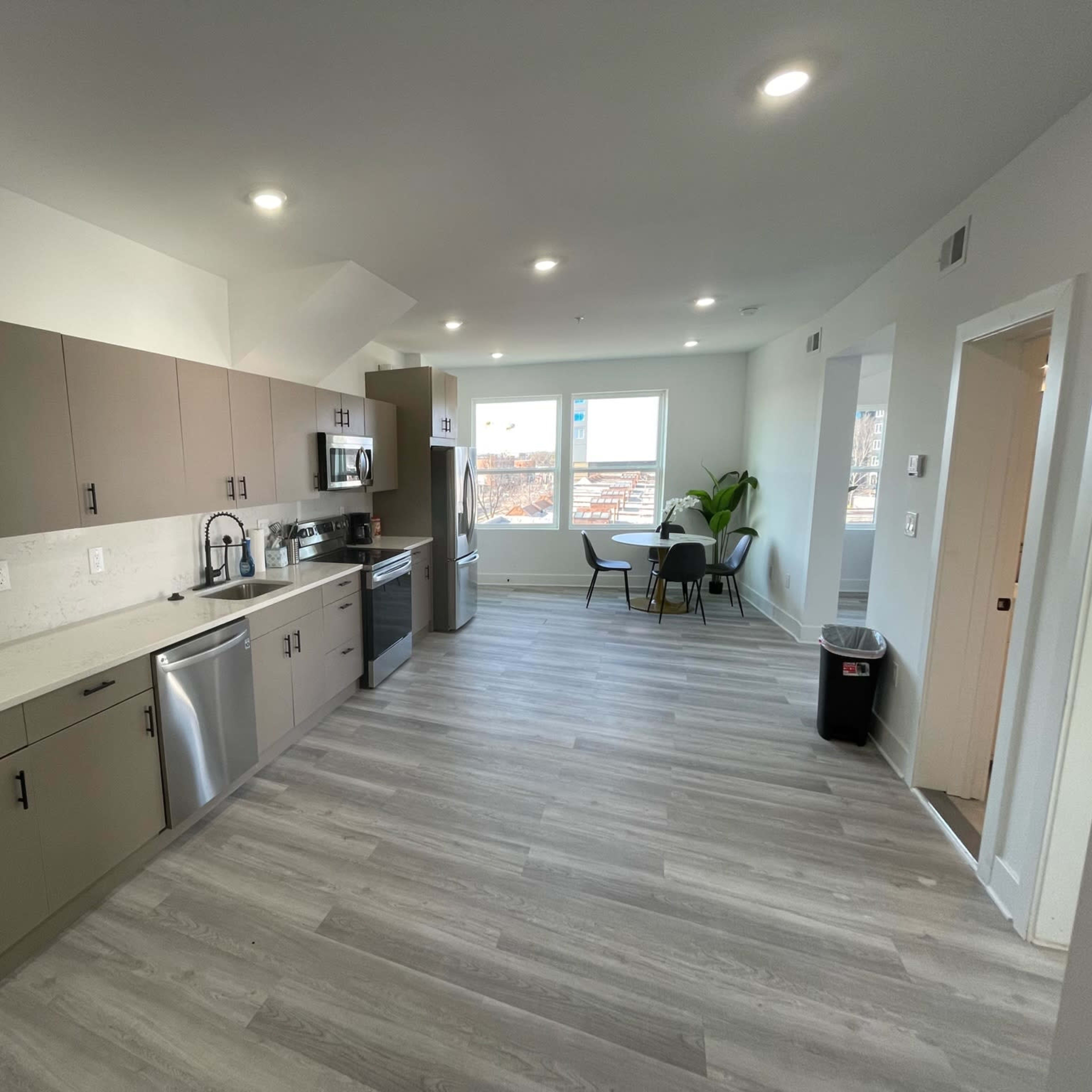 A modern kitchen with light-colored cabinets, stainless steel appliances, and a dining area featuring a round table and chairs.