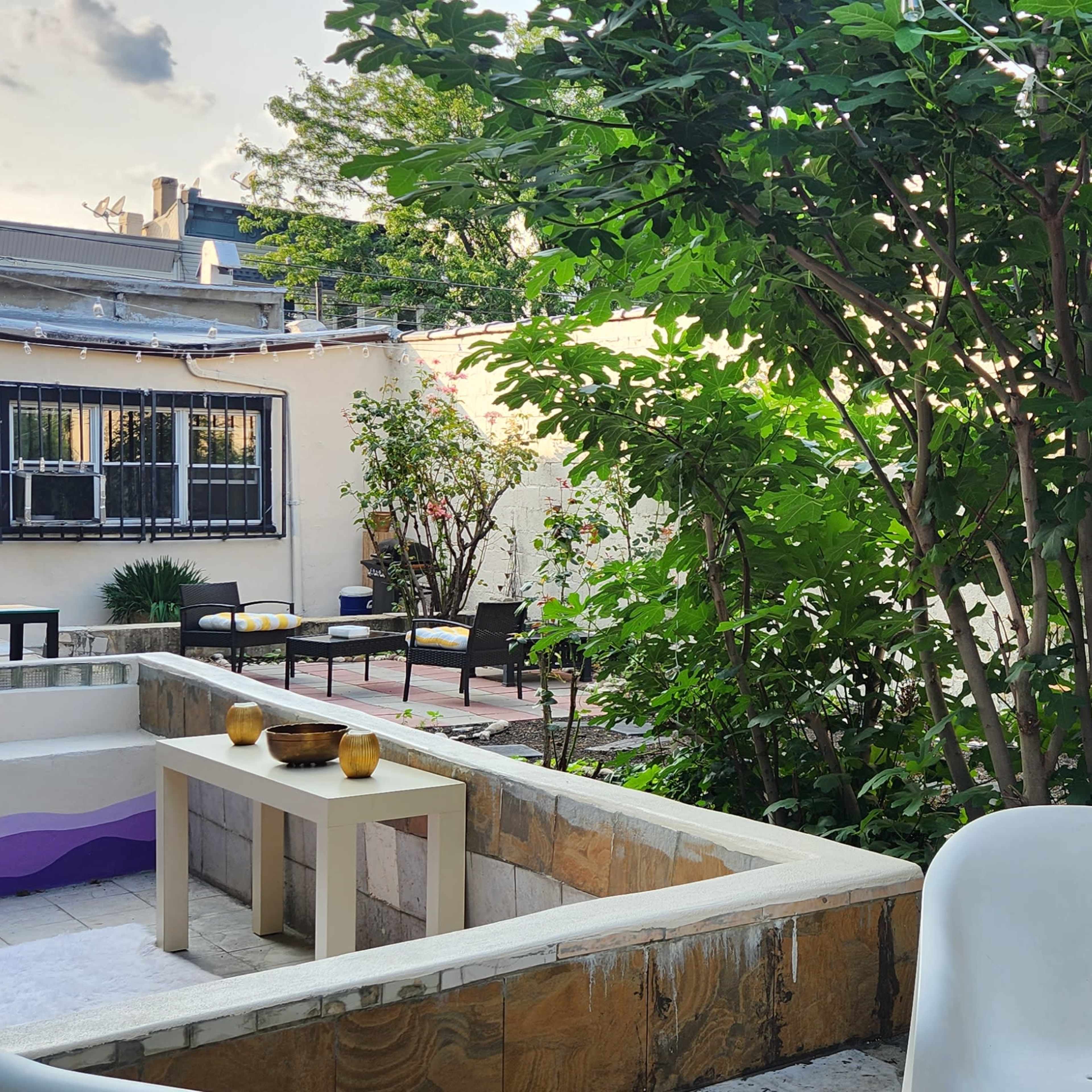 A small outdoor garden area features seating surrounded by greenery and decorative plants.