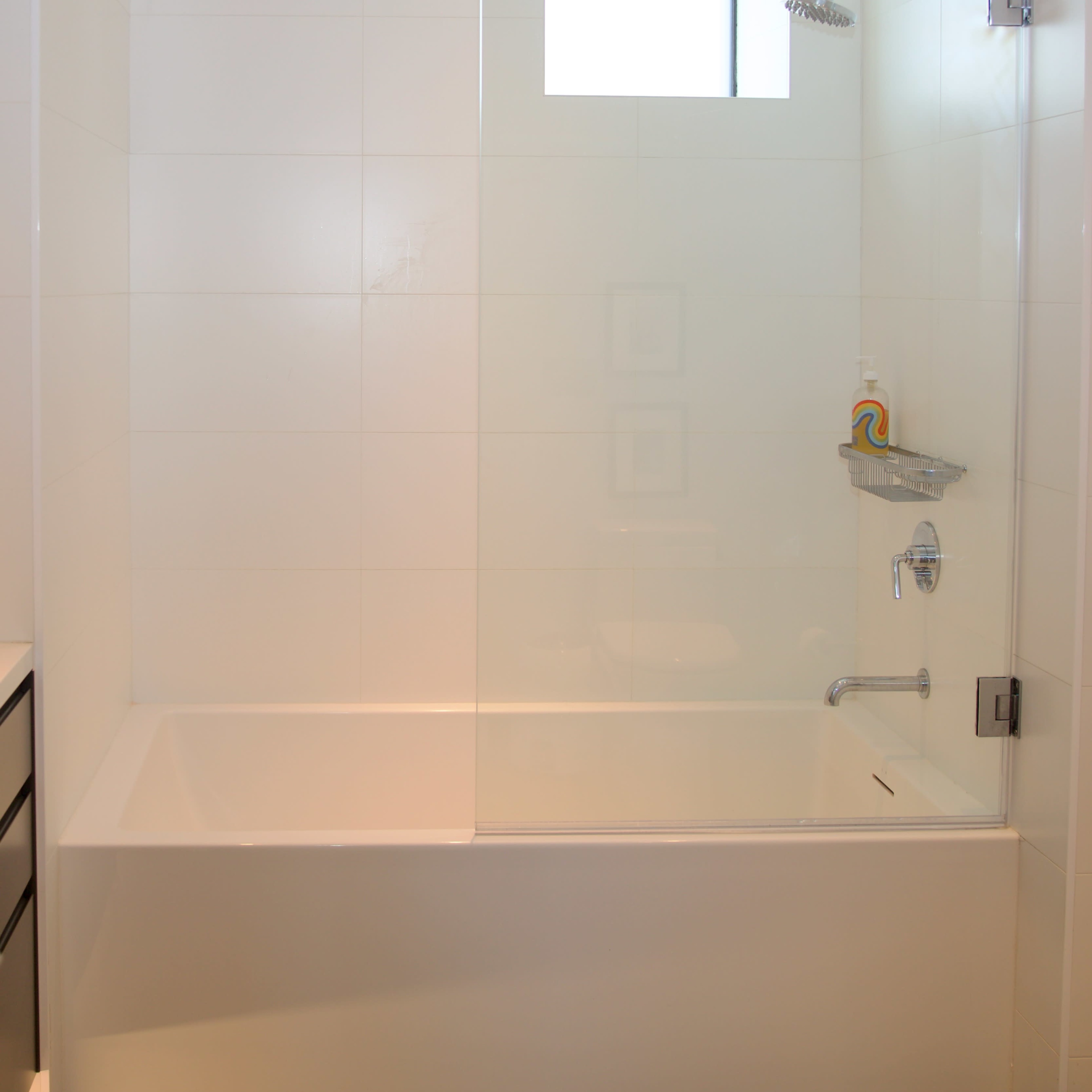 A modern bathroom featuring a bathtub with a glass shower enclosure and a showerhead mounted on the wall.