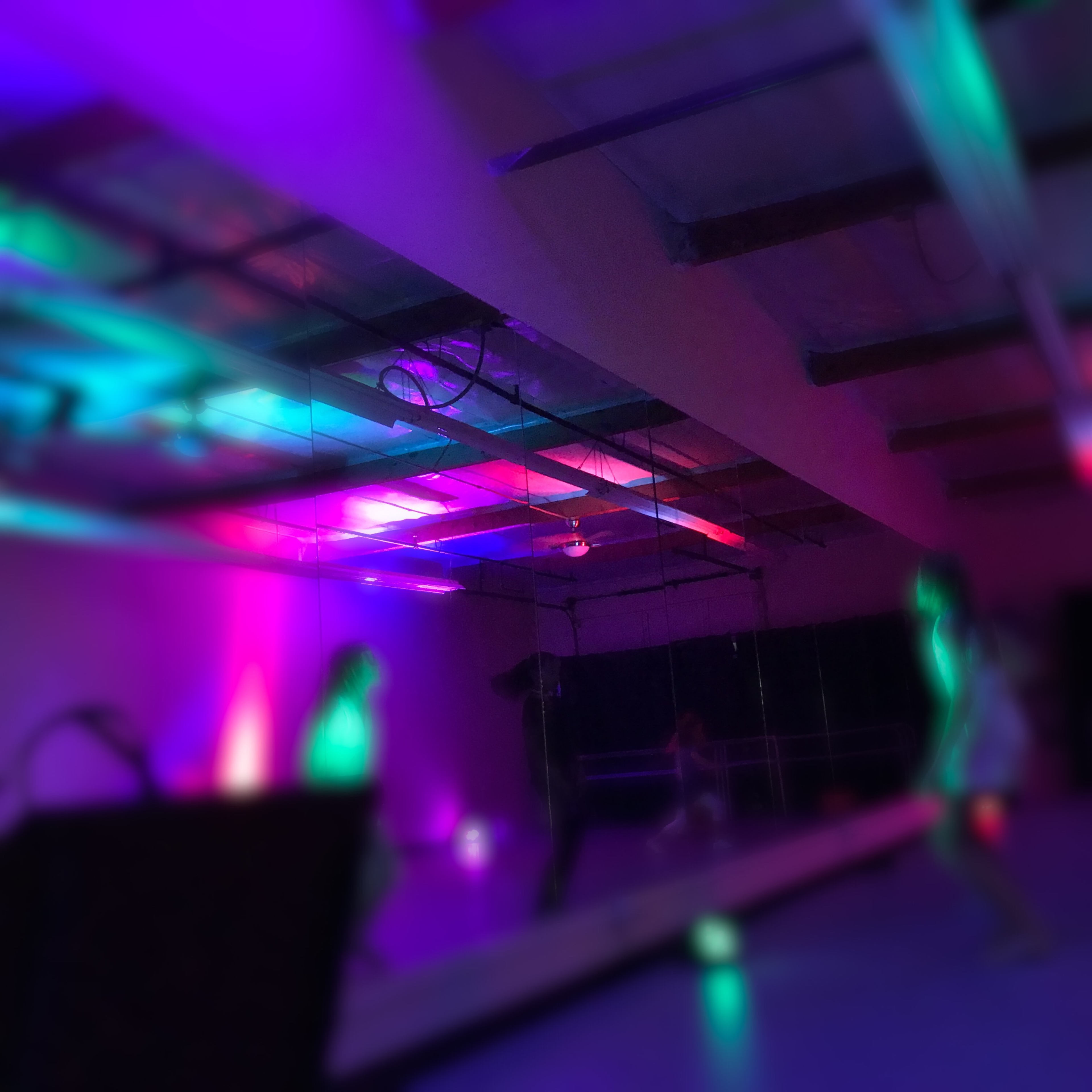 A dance studio with colorful lighting and dancers in motion.