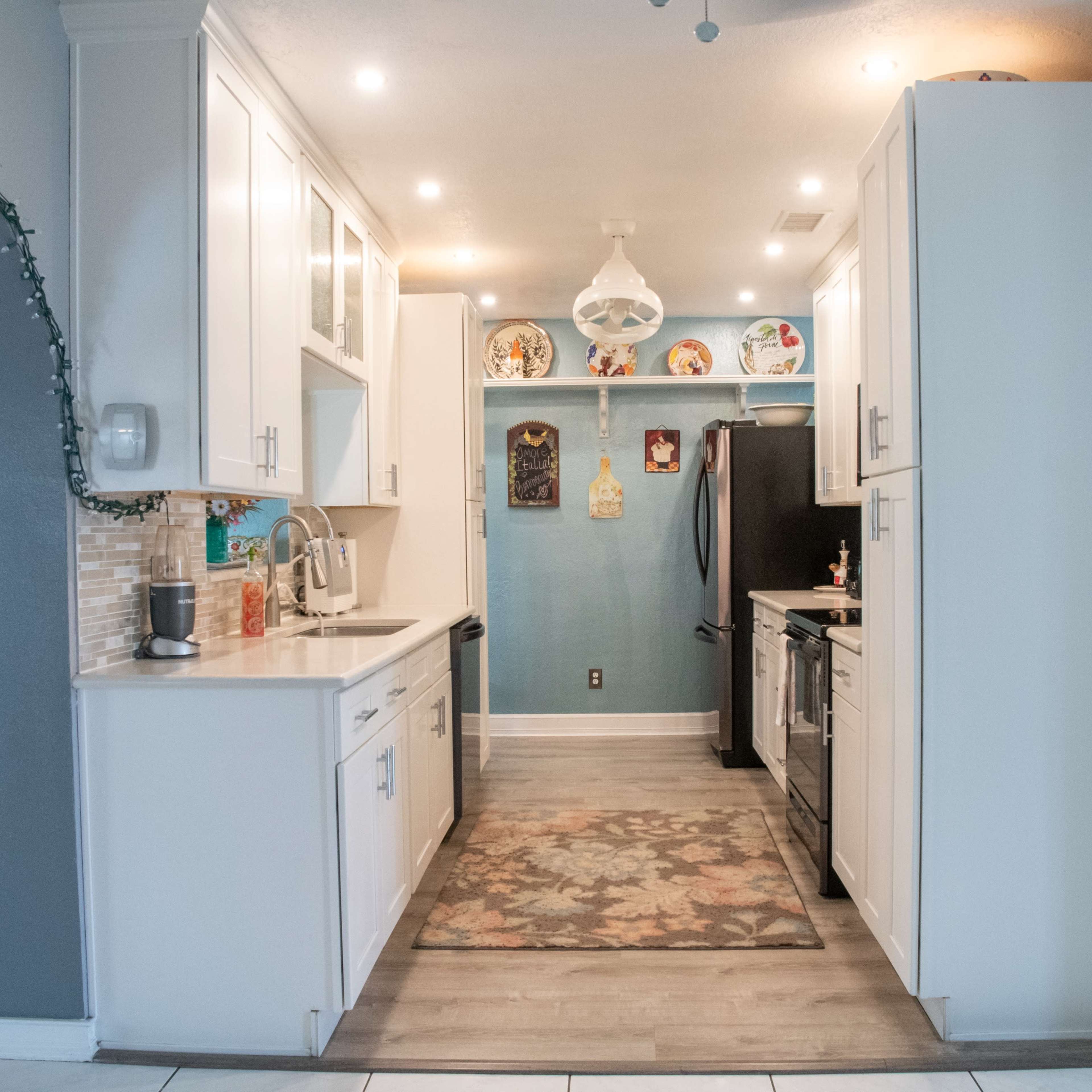 A modern kitchen with white cabinets, stainless steel appliances, and a patterned rug on the floor.