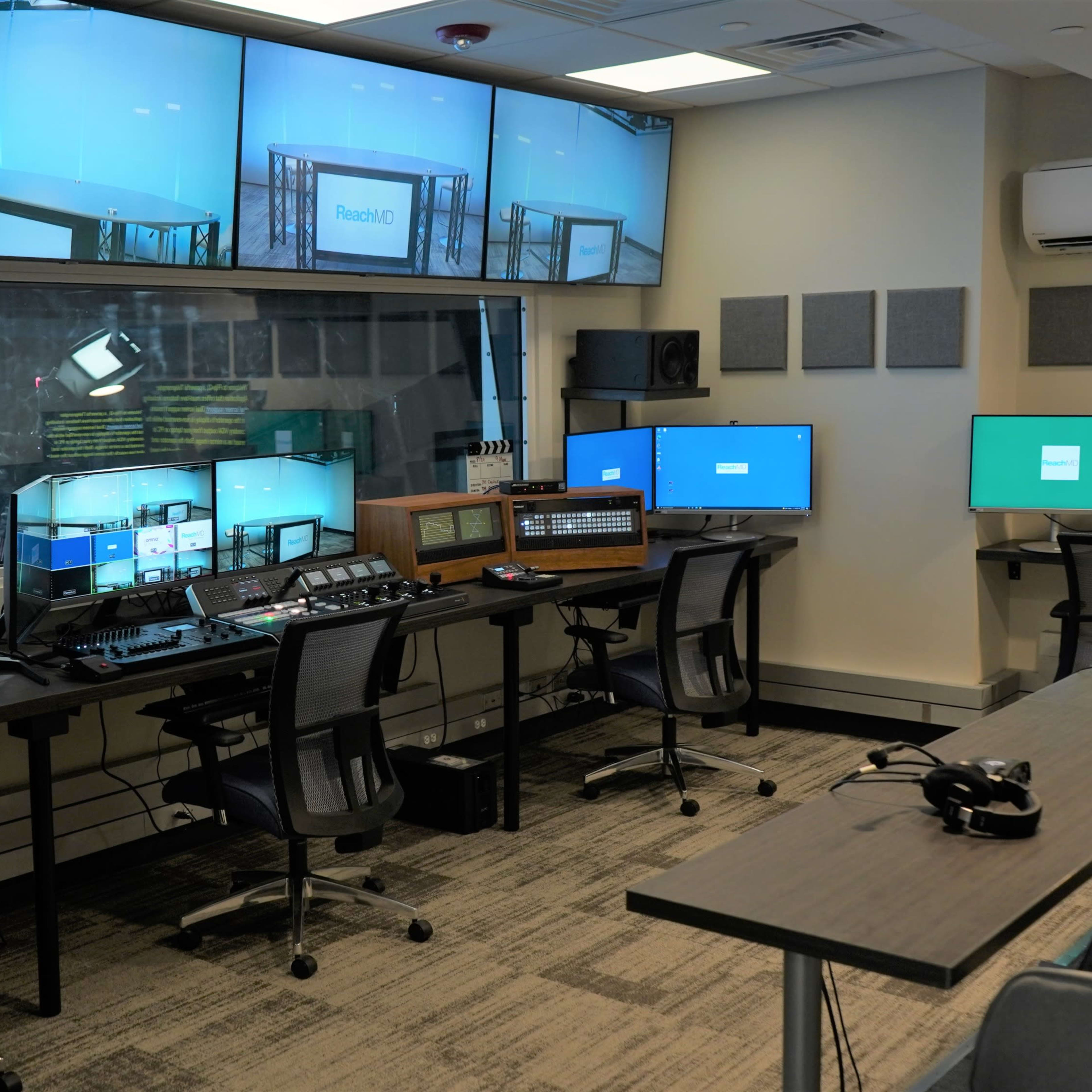 A modern television control room equipped with multiple monitors, editing stations, and broadcasting equipment arranged around a central workspace.