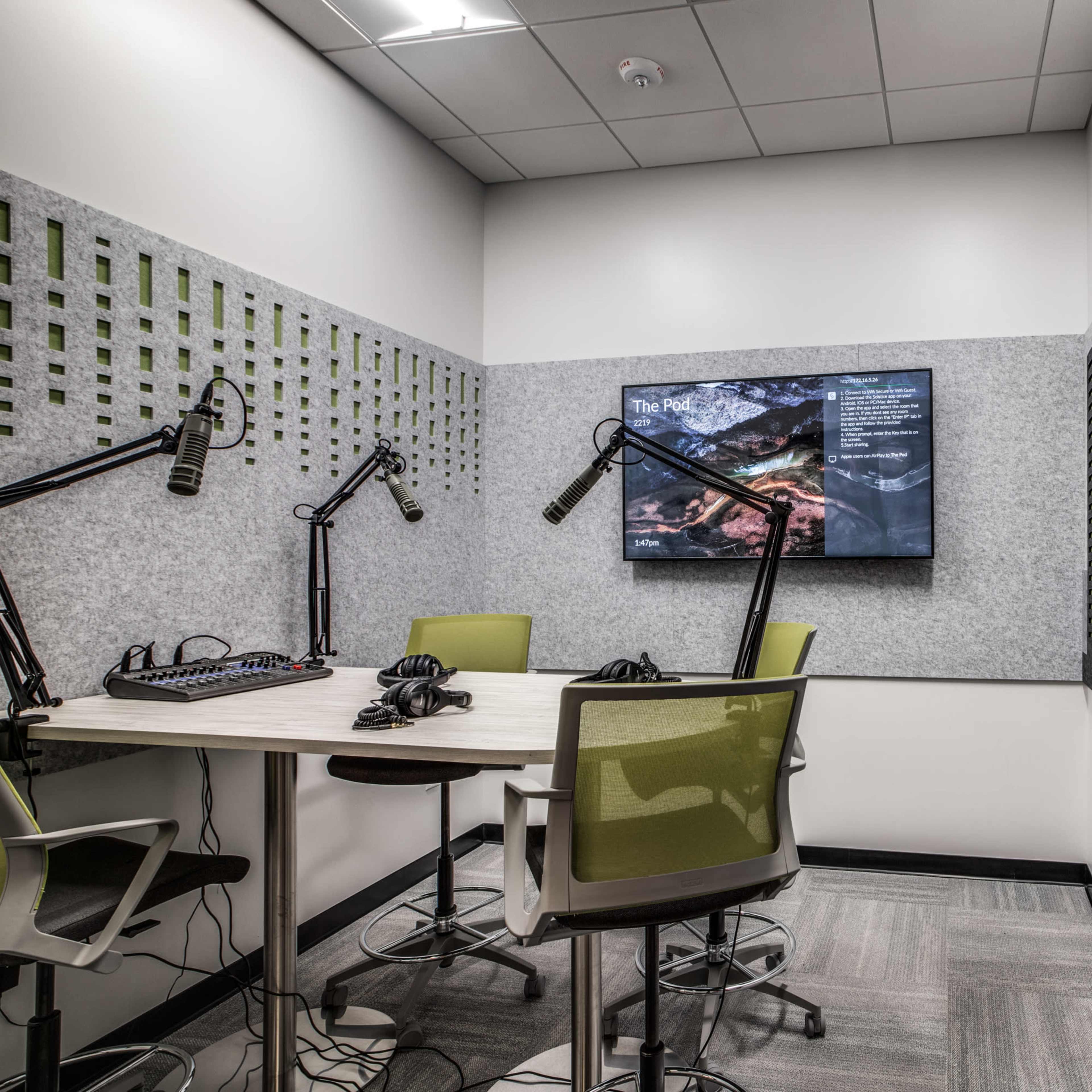 A small meeting room equipped with a large screen, microphones, and seating for discussions.