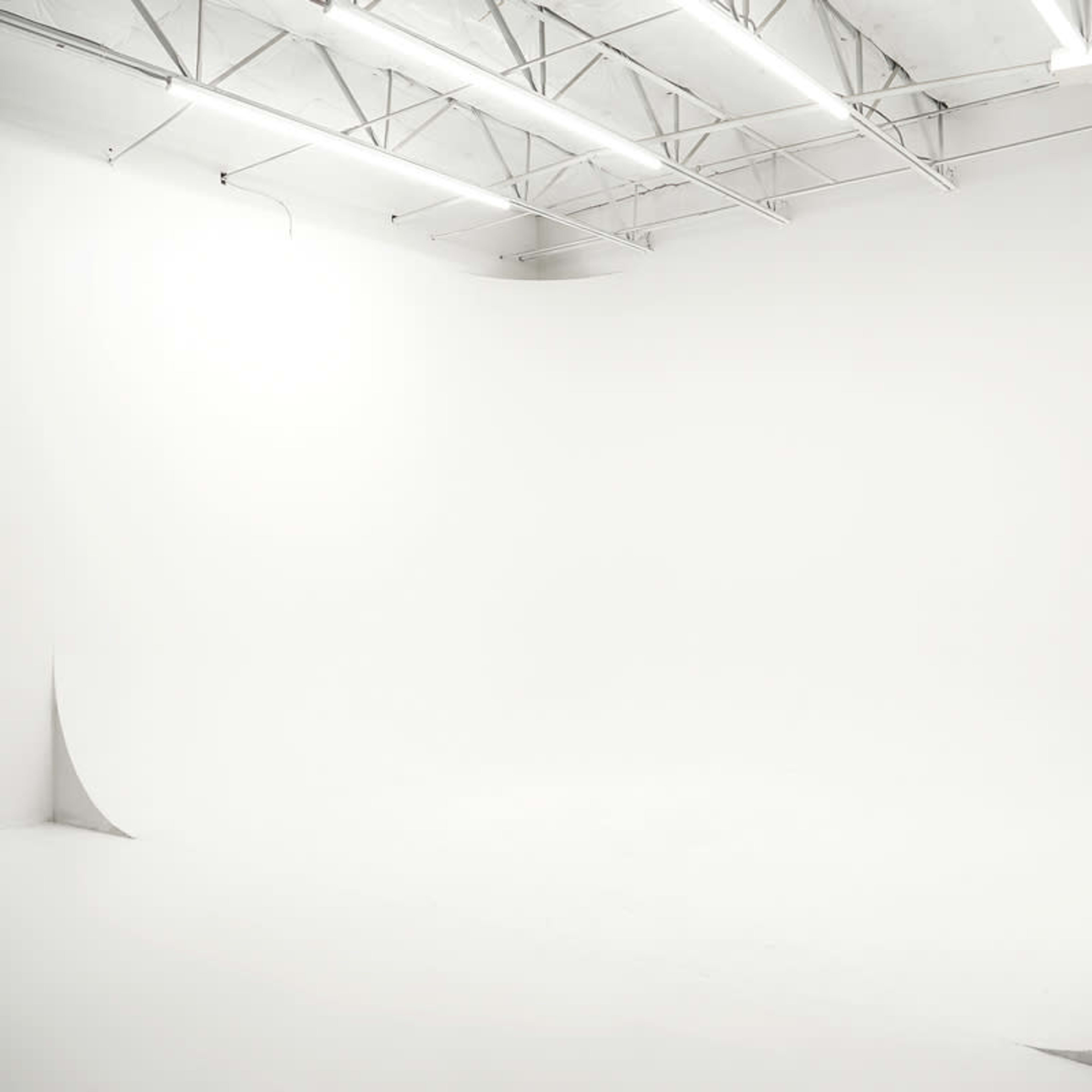 A spacious, well-lit photography studio with a seamless white backdrop and minimalist design.