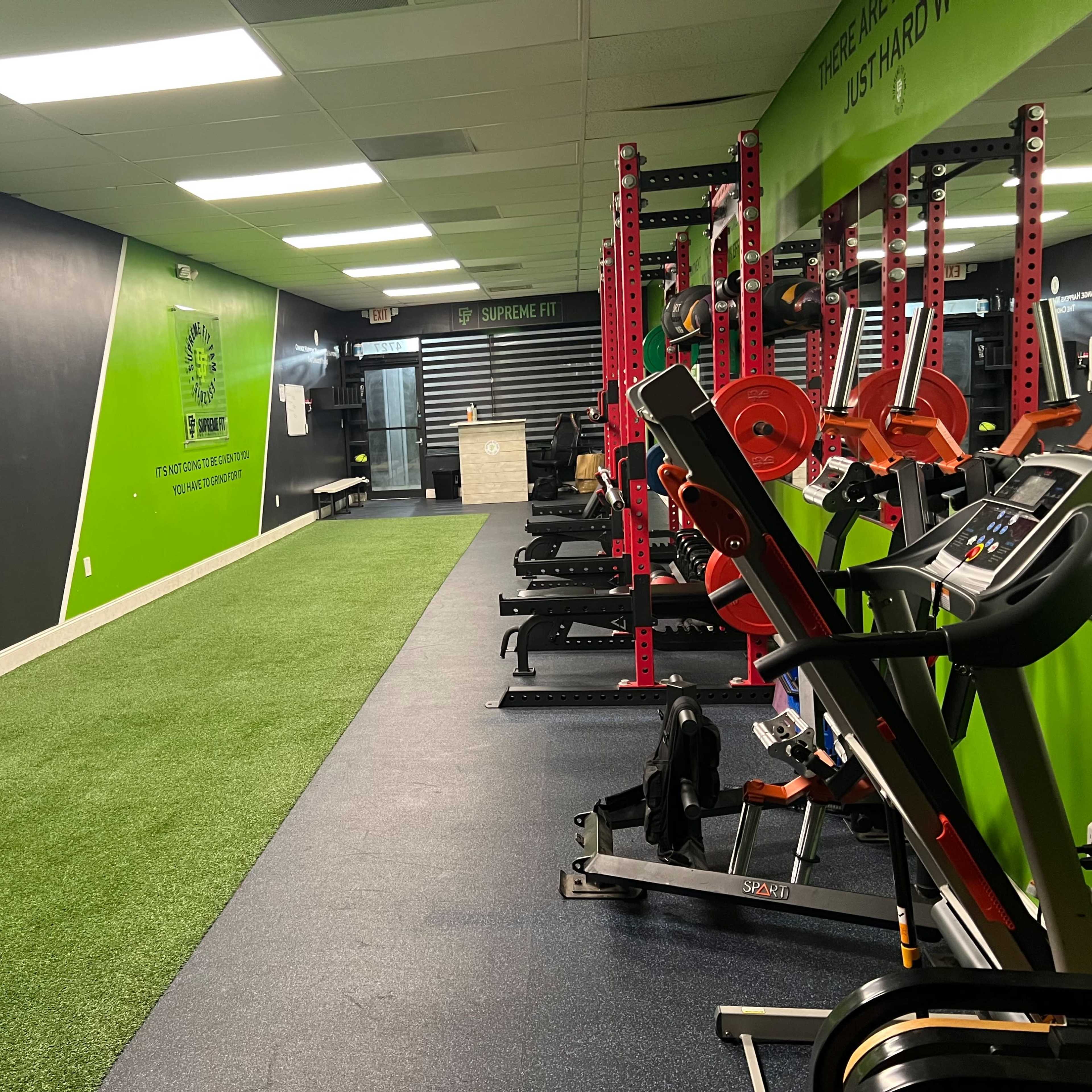 A gym interior with weightlifting equipment, cardio machines, and motivational wall graphics.
